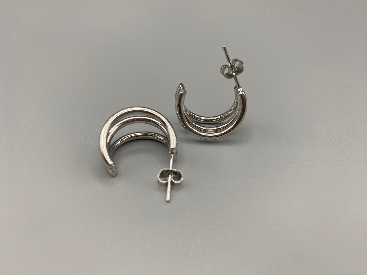 “Trinity 3 Band C Shaped Earrings Silver: A perfect blend of elegance and modern design, featuring sleek silver plating, a unique three-band C shape, and durable stainless steel construction. Ideal for both everyday wear and special occasions.”