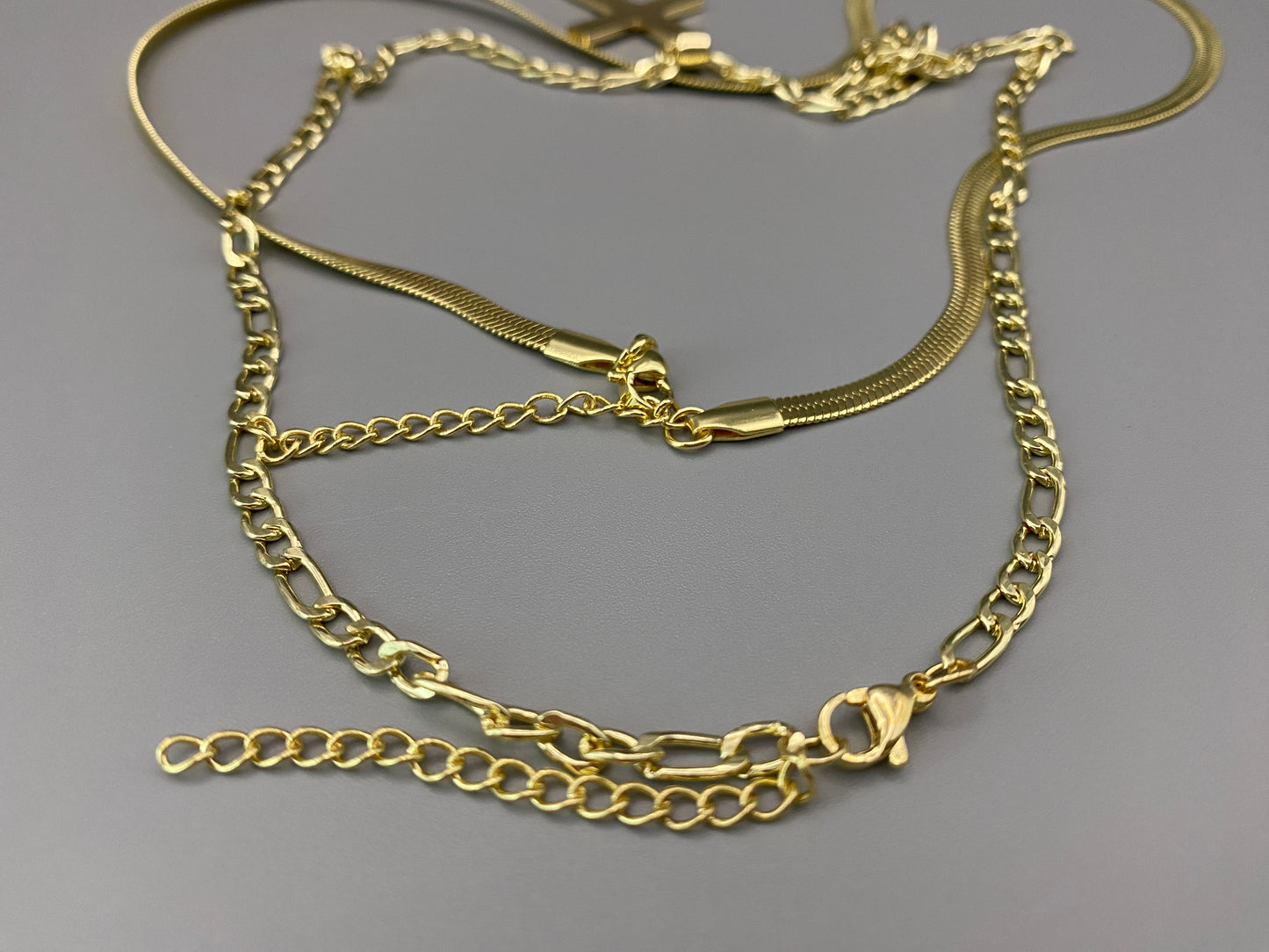 “Men’s Twin Chain Cross Necklace: A stylish 18k gold plated stainless steel necklace featuring a twin chain design with a gold cross pendant. Perfect for teens and adults, this fine jewelry piece is unisex and measures 45 cm with a 5 cm extender.”