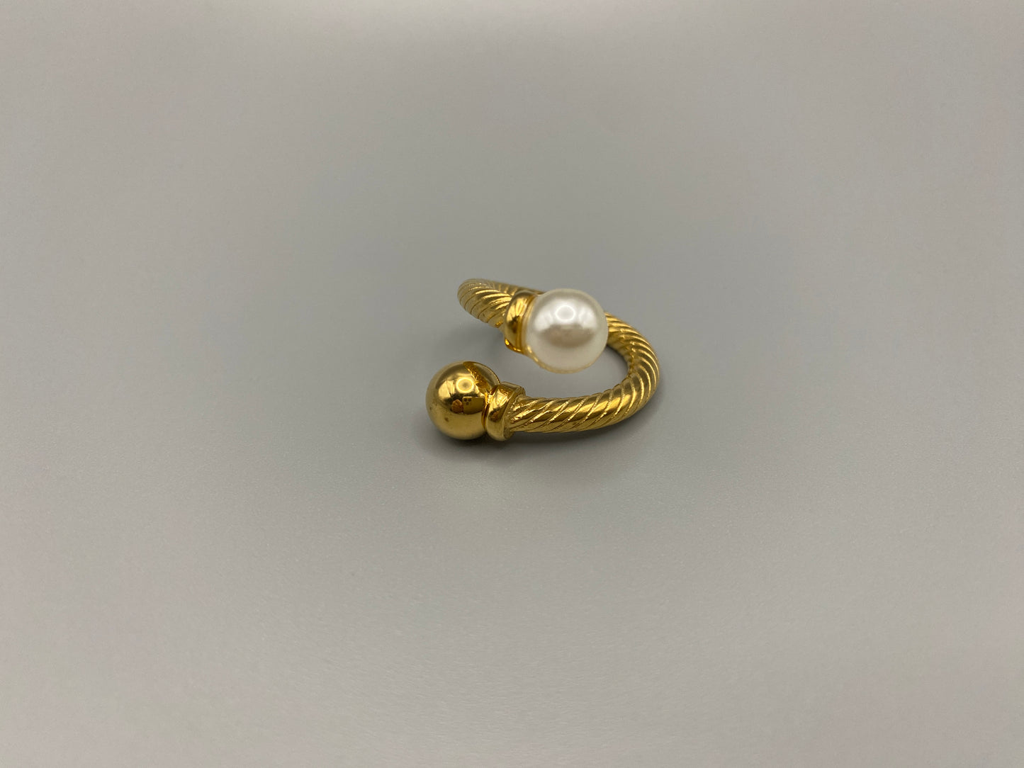 Twisted Elegance Pearl and Gold Ring: Features 18k PVD gold plating for a luxurious and durable finish. The twisted design adds a unique and elegant touch, while the pearl inlay is securely set in a claw setting. This ring is nickel-free and lead-free, making it safe for sensitive skin. It is also waterproof and non-tarnish, ensuring long-lasting beauty and wearability. Available in size 6 for a comfortable fit. Perfect for those who seek both style and substance in their jewellery.