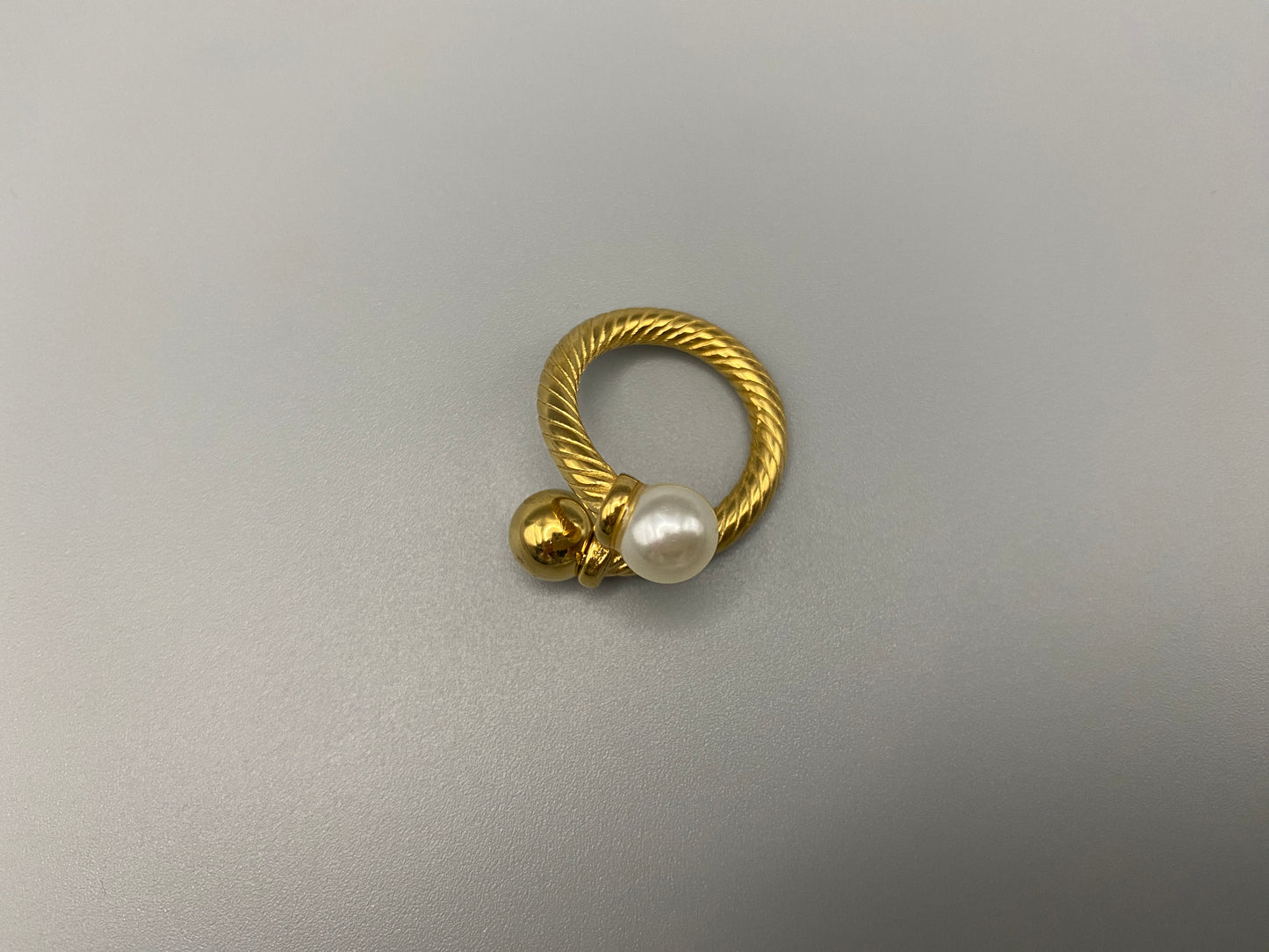 Twisted Elegance Pearl and Gold Ring: Features 18k PVD gold plating for a luxurious and durable finish. The twisted design adds a unique and elegant touch, while the pearl inlay is securely set in a claw setting. This ring is nickel-free and lead-free, making it safe for sensitive skin. It is also waterproof and non-tarnish, ensuring long-lasting beauty and wearability. Available in size 6 for a comfortable fit. Perfect for those who seek both style and substance in their jewellery.