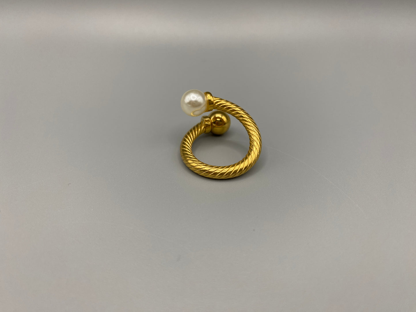 Twisted Elegance Pearl and Gold Ring: Features 18k PVD gold plating for a luxurious and durable finish. The twisted design adds a unique and elegant touch, while the pearl inlay is securely set in a claw setting. This ring is nickel-free and lead-free, making it safe for sensitive skin. It is also waterproof and non-tarnish, ensuring long-lasting beauty and wearability. Available in size 6 for a comfortable fit. Perfect for those who seek both style and substance in their jewellery.