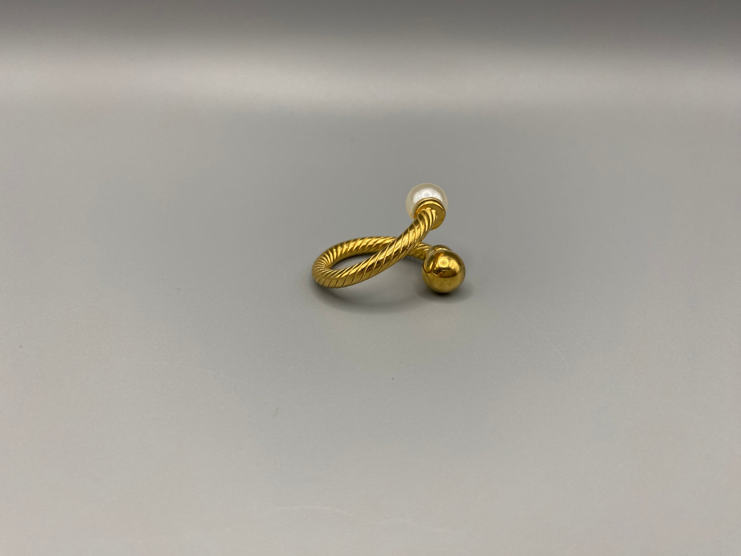 Twisted Elegance Pearl and Gold Ring: Features 18k PVD gold plating for a luxurious and durable finish. The twisted design adds a unique and elegant touch, while the pearl inlay is securely set in a claw setting. This ring is nickel-free and lead-free, making it safe for sensitive skin. It is also waterproof and non-tarnish, ensuring long-lasting beauty and wearability. Available in size 6 for a comfortable fit. Perfect for those who seek both style and substance in their jewellery.