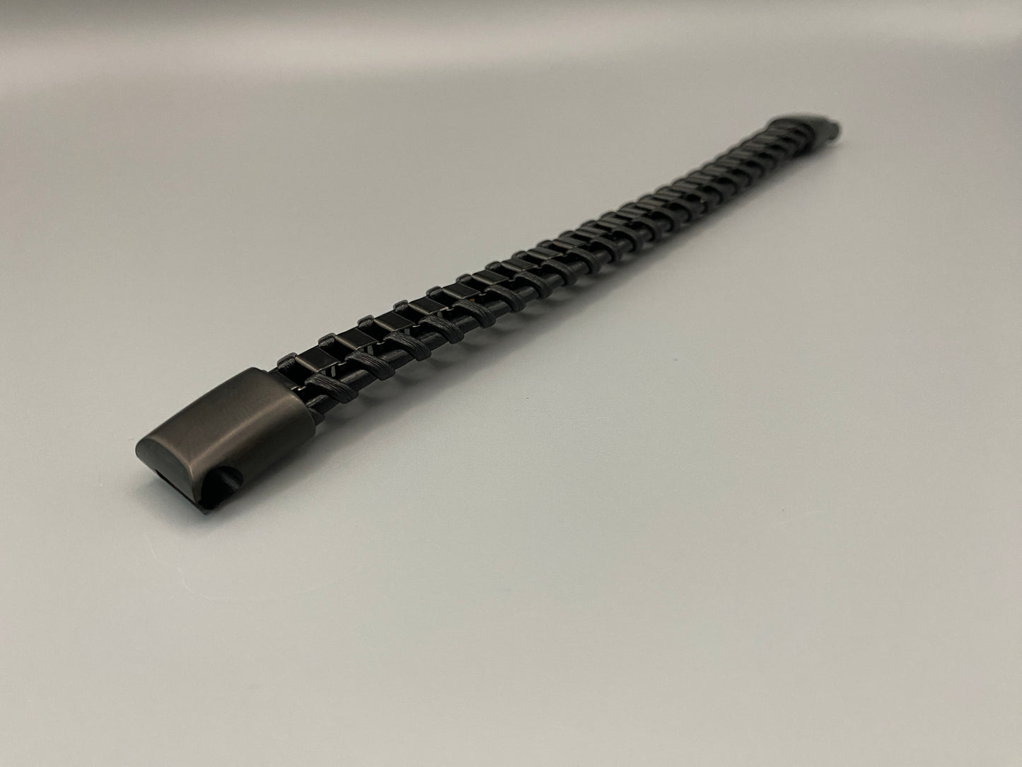 “Urban Edge Wrist Wear Men’s Bracelet in black, crafted from premium stainless steel with a casual and sporty design. Measures 19 cm in length, available in Black Zinc Plated, 18K Gold Plated, and Silver Plated finishes. Features inlay technology for added detail and craftsmanship.”