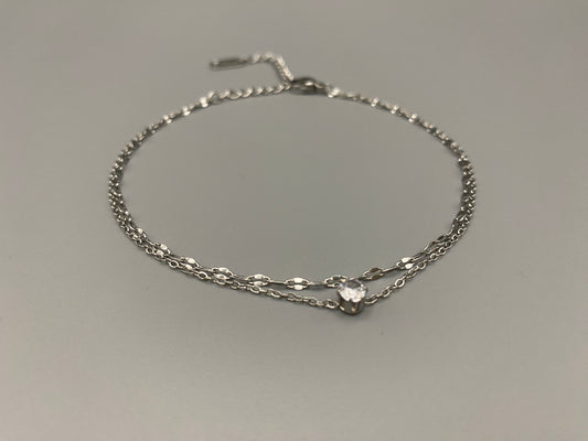 “Aurora Twin Chain Bracelet in silver with a sophisticated twin chain design, adorned with sparkling zirconia gemstones. Waterproof and measures 18 cm with a 3 cm extender for adjustable fit.”
