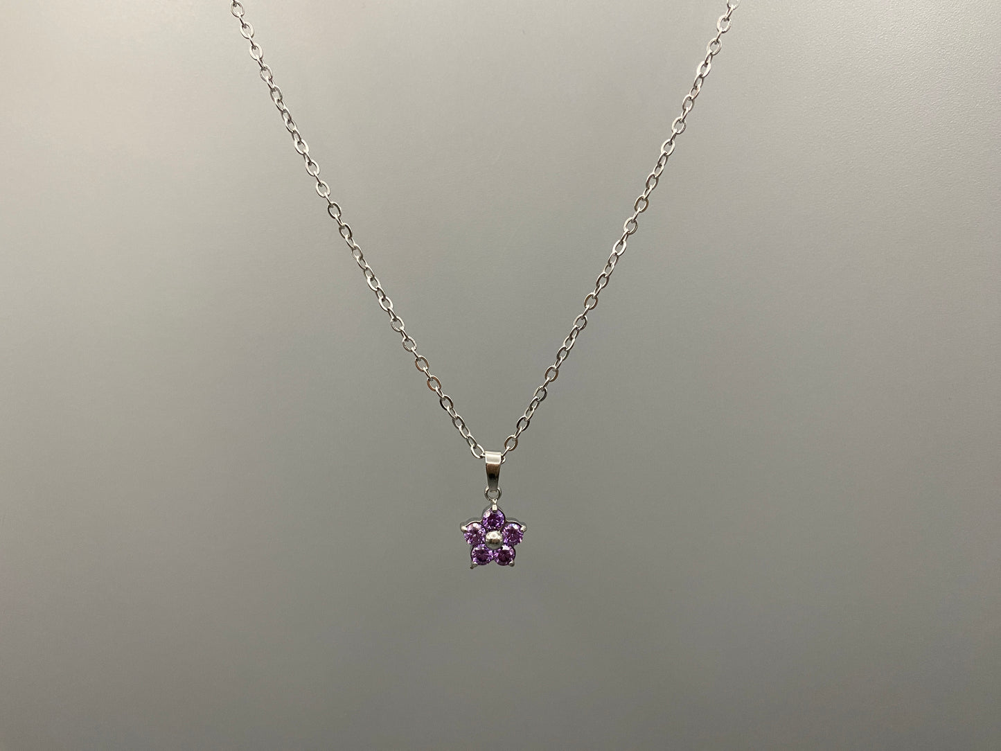 “Blossom Silver Pendant Necklace with a plum blossom design, featuring colourful cubic zirconia stones in a claw setting. Made from durable stainless steel with PVD plating. Measures 46 cm with a 5 cm adjustment.”