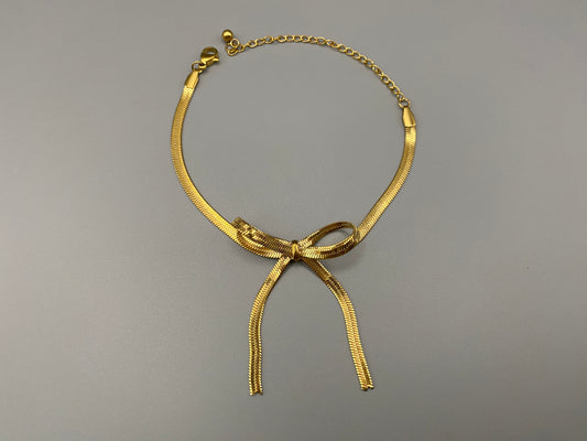 “Celest Angel Bow Bracelet in gold featuring a delicate bow design, made of stainless steel for durability and tarnish resistance. Measures 18 cm with a 3 cm extender for adjustable fit.”