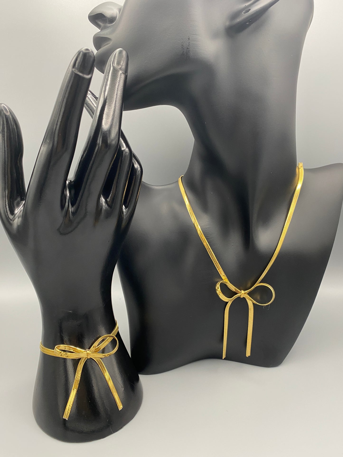 “The Celest Angel Bow Bracelet in gold features a delicate bow design. It is made of stainless steel for durability and tarnish resistance. The bracelet measures 18 cm with a 3 cm extender for an adjustable fit.”