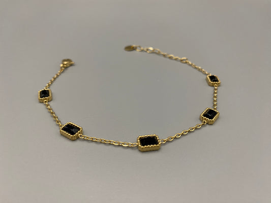 “Clarissa Bracelet in gold with black zircon inset stones, featuring a luxurious gold plating and adjustable length of 17.5 cm with a 2 cm extension. Durable construction ensures long-lasting wear and tarnish resistance.”