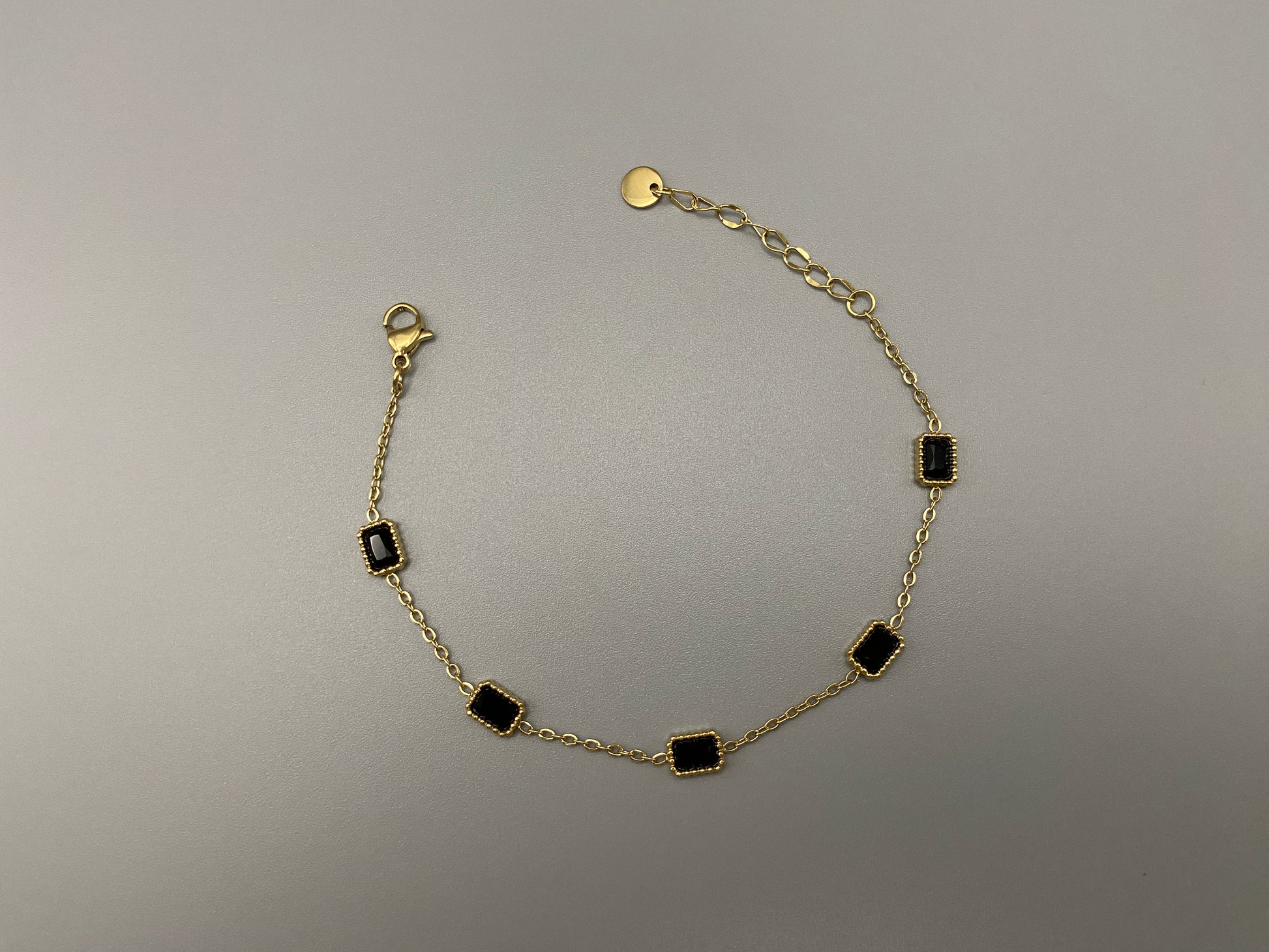 “Clarissa Bracelet in gold with black zircon inset stones, featuring a luxurious gold plating and adjustable length of 17.5 cm with a 2 cm extension. Durable construction ensures long-lasting wear and tarnish resistance.”