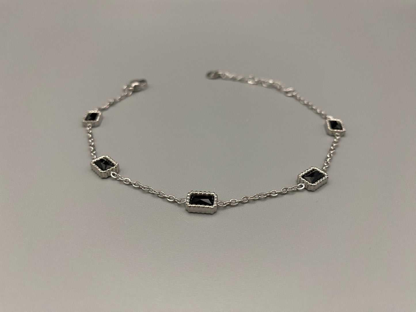 “Clarissa Bracelet in silver with black zircon inset stones, featuring a luxurious silver plating and adjustable length of 17.5 cm with a 2 cm extension. Durable construction ensures long-lasting wear and tarnish resistance.”