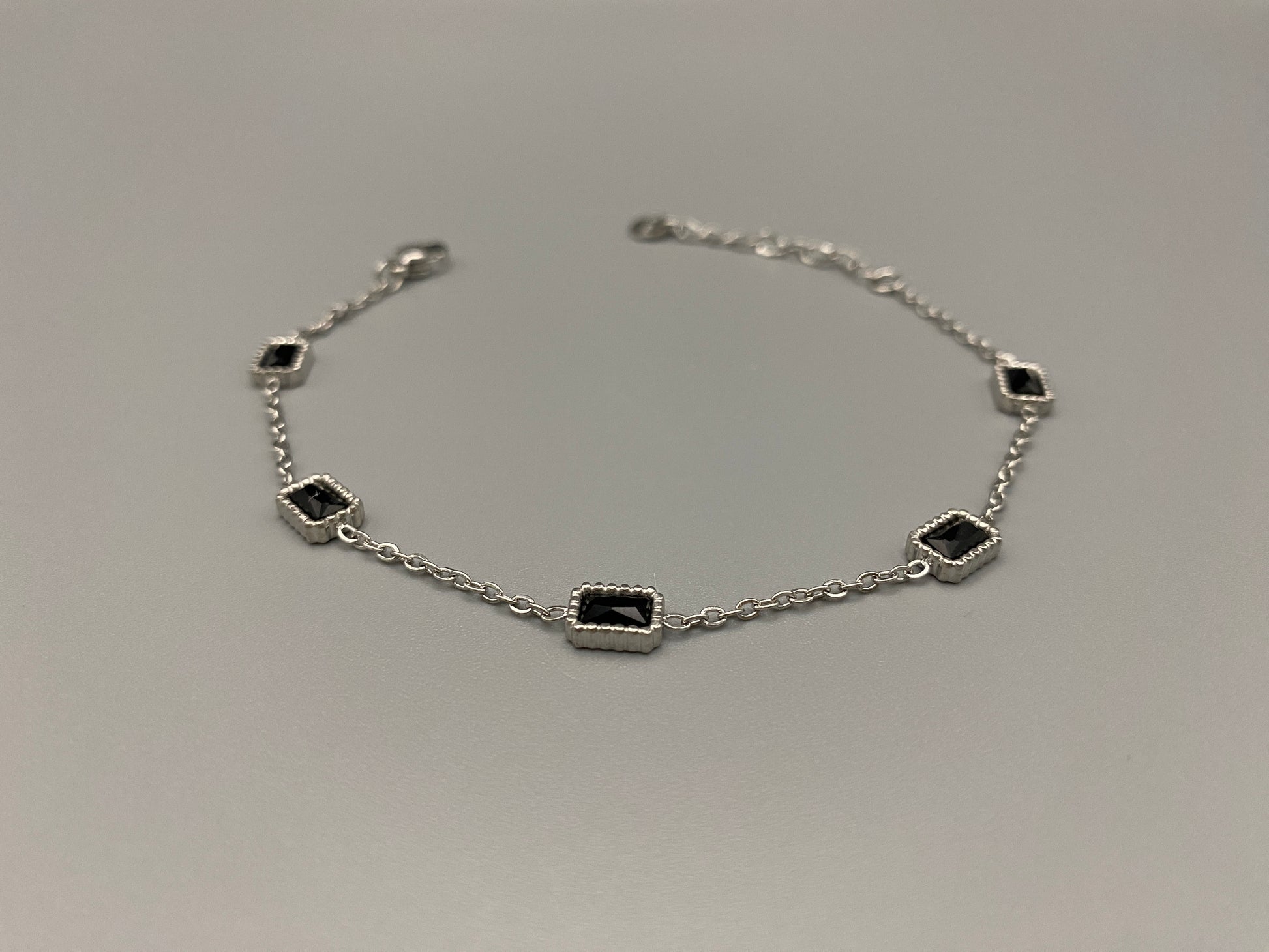 “Clarissa Bracelet in silver with black zircon inset stones, featuring a luxurious silver plating and adjustable length of 17.5 cm with a 2 cm extension. Durable construction ensures long-lasting wear and tarnish resistance.”