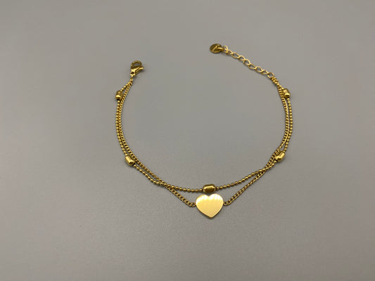“Cora Twin Chain Heart and Bead Bracelet in gold, featuring a romantic twin chain design with heart and bead accents. 18K gold plated, made from durable titanium steel with PVD plating. Measures 17 cm with a 3 cm extender for adjustable fit.”