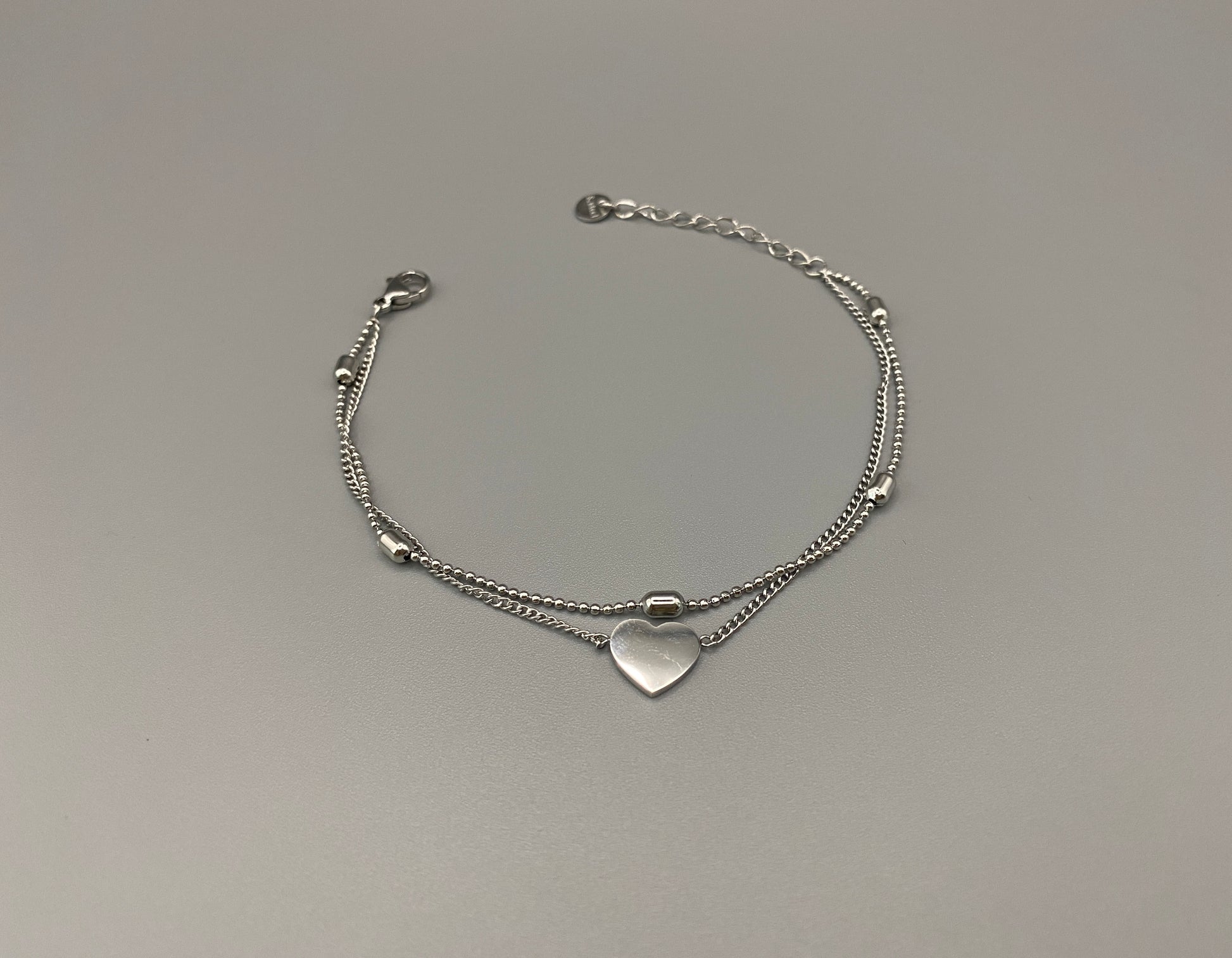 “Cora Twin Chain Heart and Bead Bracelet in gold, featuring a romantic twin chain design with heart and bead accents. silver plated, made from durable titanium steel with PVD plating. Measures 17 cm with a 3 cm extender for adjustable fit.”