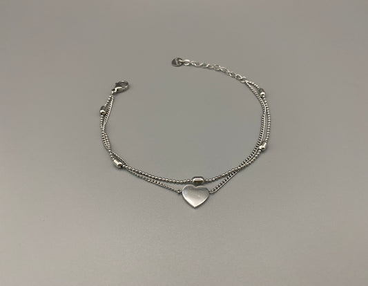 “Cora Twin Chain Heart and Bead Bracelet in gold, featuring a romantic twin chain design with heart and bead accents. silver plated, made from durable titanium steel with PVD plating. Measures 17 cm with a 3 cm extender for adjustable fit.”