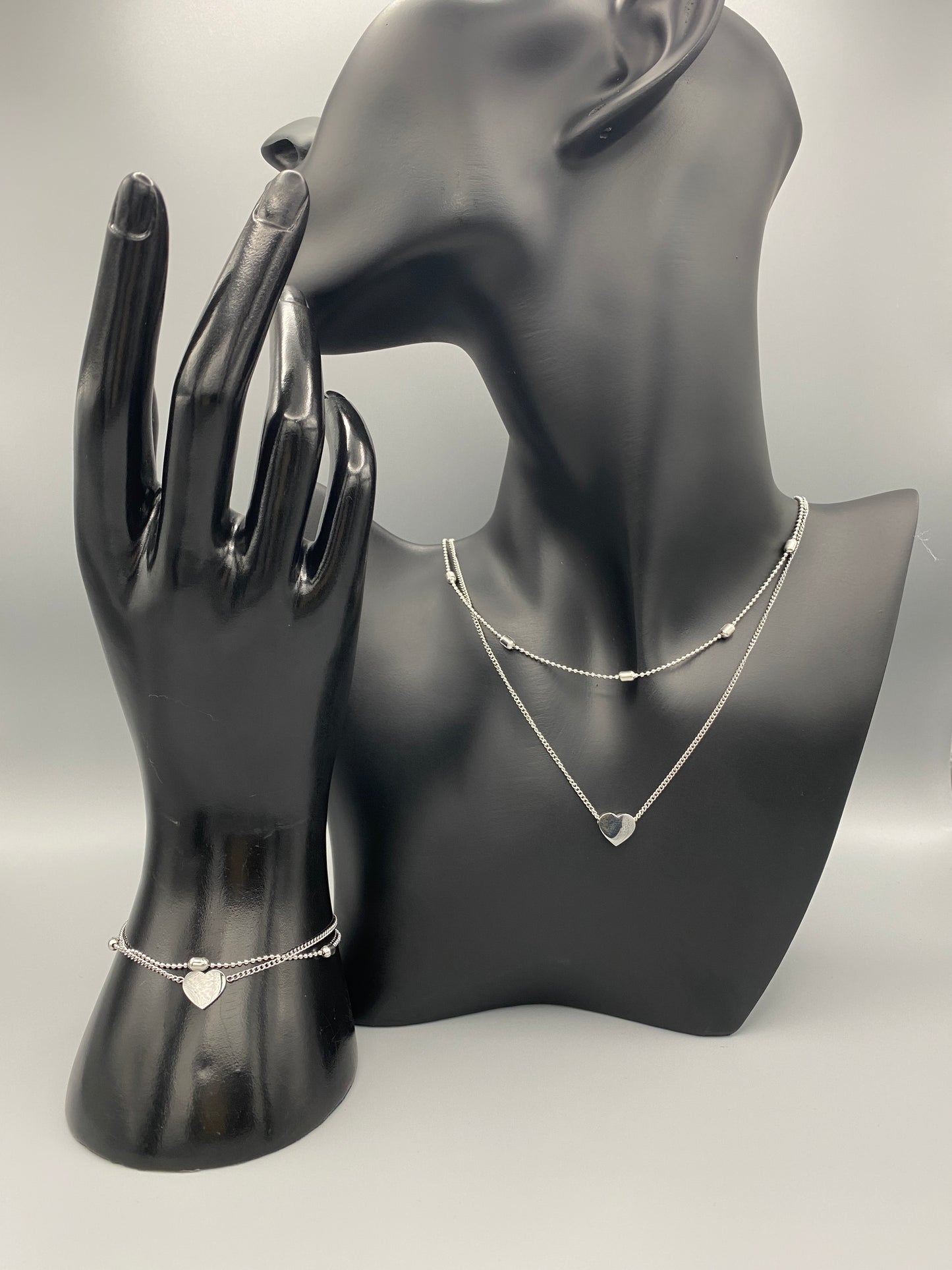 Cora Twin Chain Heart and Bead Necklace in Silver. Features: Durable Material: Crafted from stainless steel, known for its strength and resistance to tarnish. Elegant Design: The twin chain design with beads and heart elements adds a touch of sophistication. Adjustable Length: Measures 41 cm with an additional 5 cm extension for a customizable and comfortable fit. PVD Plating: Provides enhanced durability and resistance to wear, ensuring lasting beauty.
