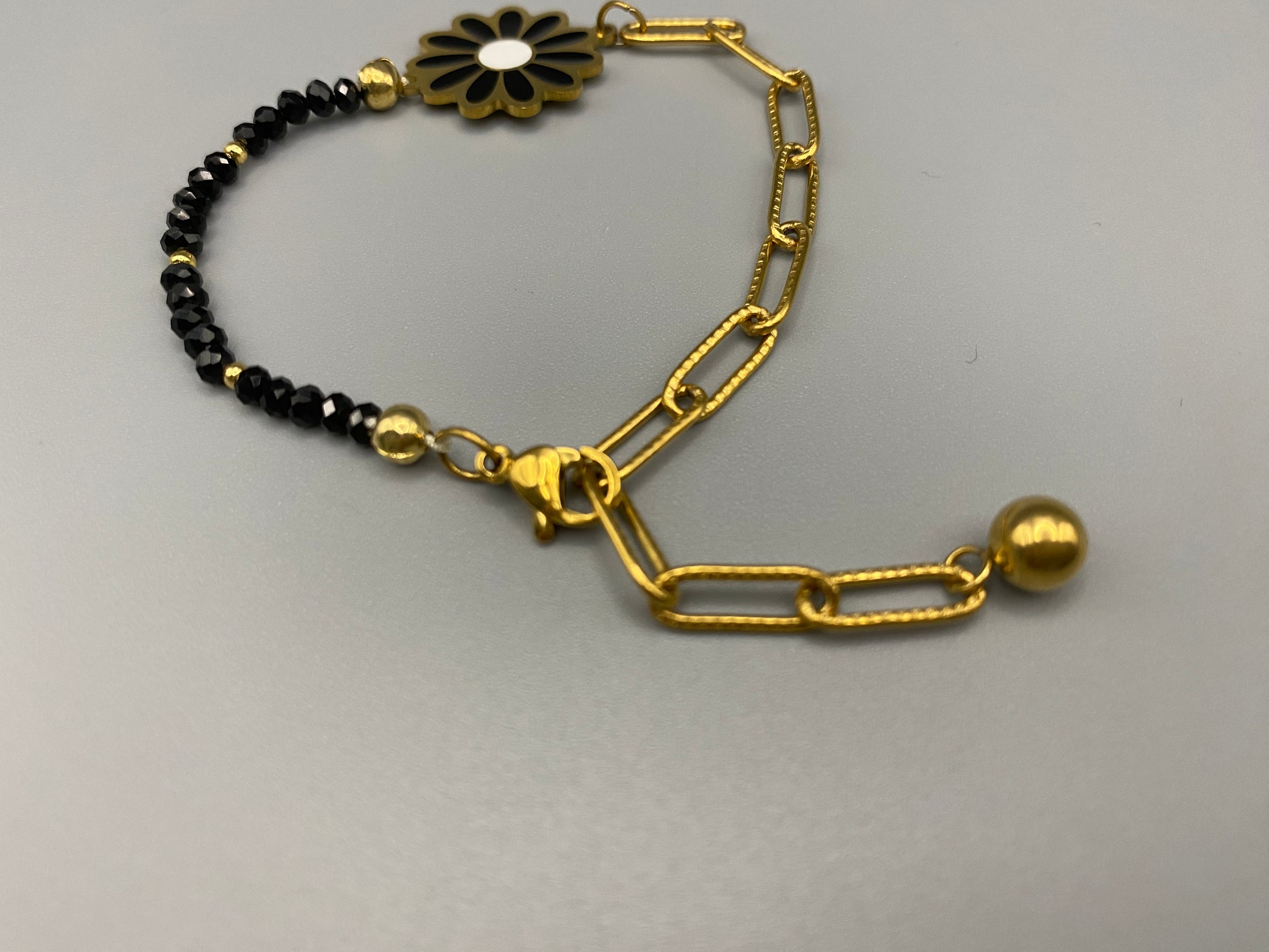 Daisy Chain Bead Bracelet in black, crafted from stainless steel with 18K gold plating. Features a daisy flower pattern with crystal and rhinestone accents. Eco-friendly, nickel and lead-free, safe for sensitive skin.”