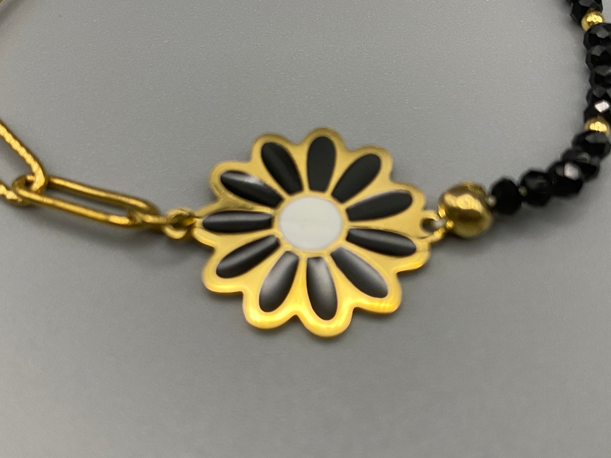 Daisy Chain Bead Bracelet in black, crafted from stainless steel with 18K gold plating. Features a daisy flower pattern with crystal and rhinestone accents. Eco-friendly, nickel and lead-free, safe for sensitive skin.”