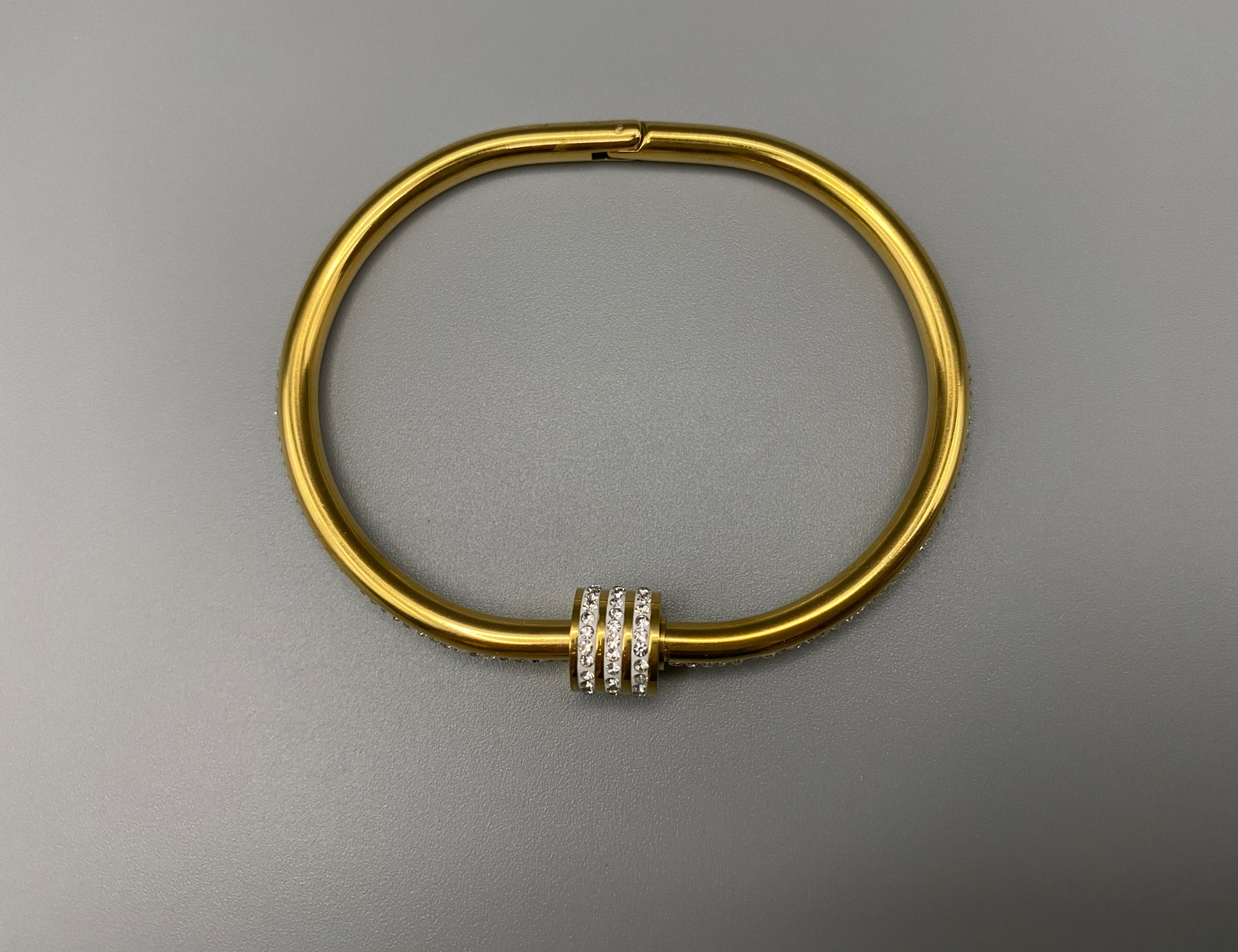 “Eclipse Encrusted Bangle Bracelet in gold with an encrusted gem inlay, featuring 18K gold plating and a thread open and close mechanism for easy adjustment. Made from high-quality materials for long-lasting wear.”