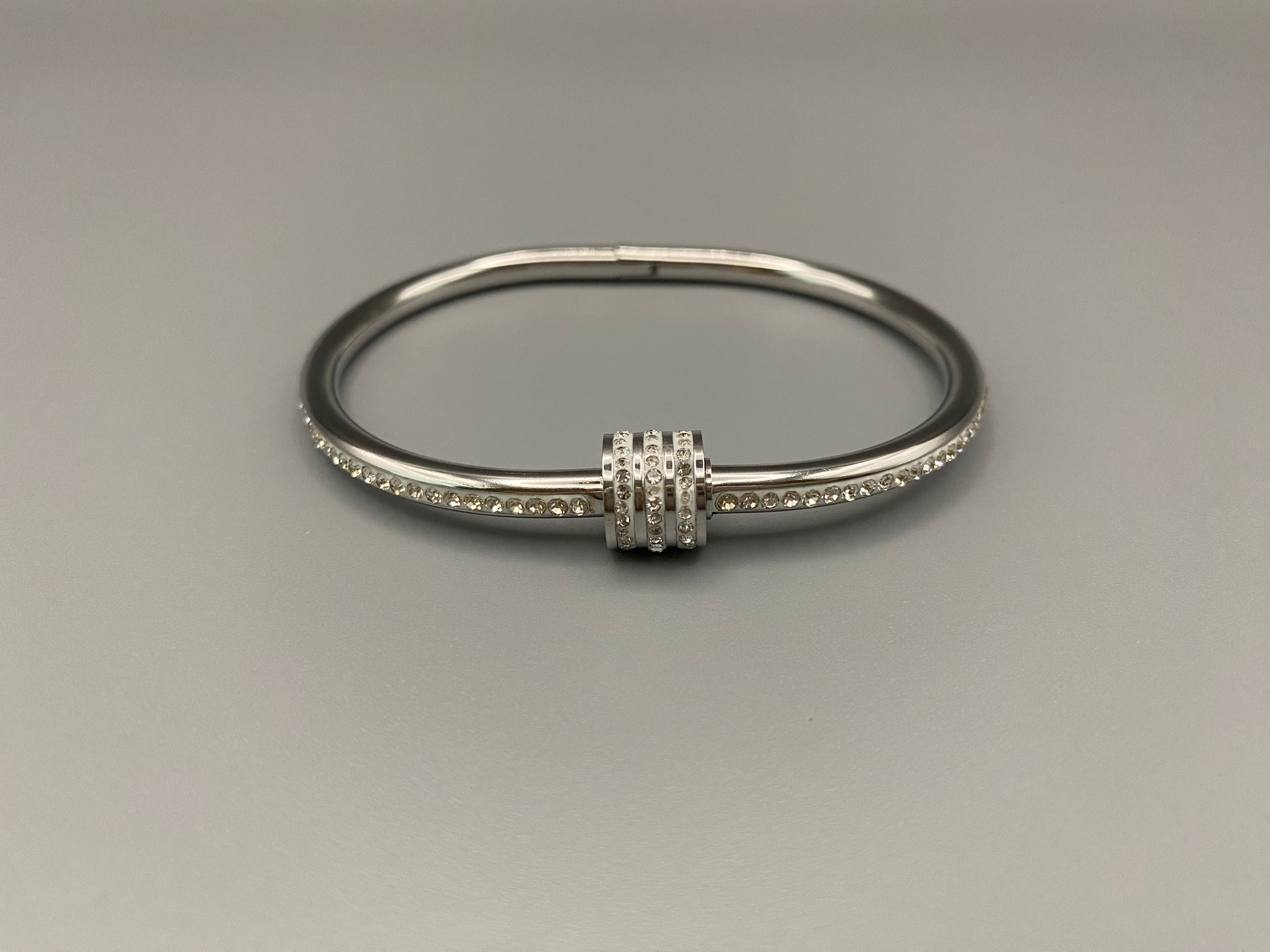 “Eclipse Encrusted Bangle Bracelet in silver with an encrusted gem inlay, featuring silver plating and a thread open and close mechanism for easy adjustment. Made from high-quality materials for long-lasting wear.”