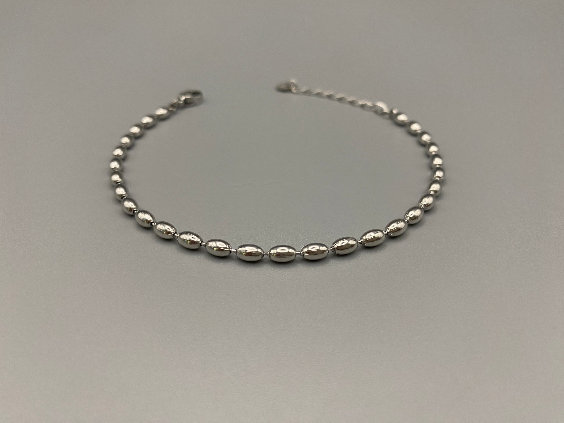 “Elliptica Bracelet in silver with connected oval-shaped links, featuring a modern and sophisticated design. Made from durable stainless steel with a silver finish. Measures 17 cm with a 3 cm extender for adjustable fit.”