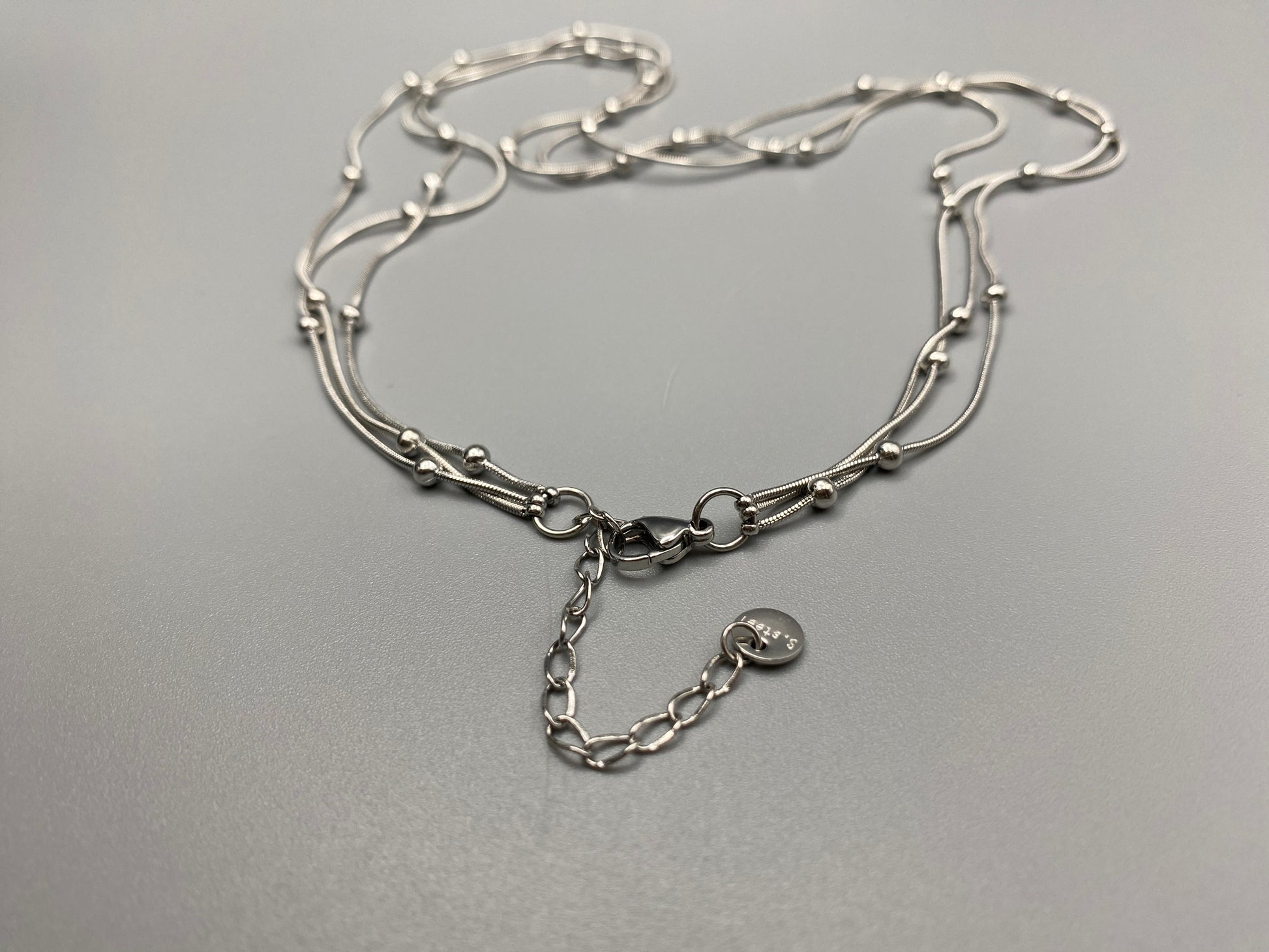 Elegant tri-chain design with bead accents. silver plated, PVD plated for durability. Adjustable length: 40 cm + 5 cm extender. Versatile for layering or solo wear.