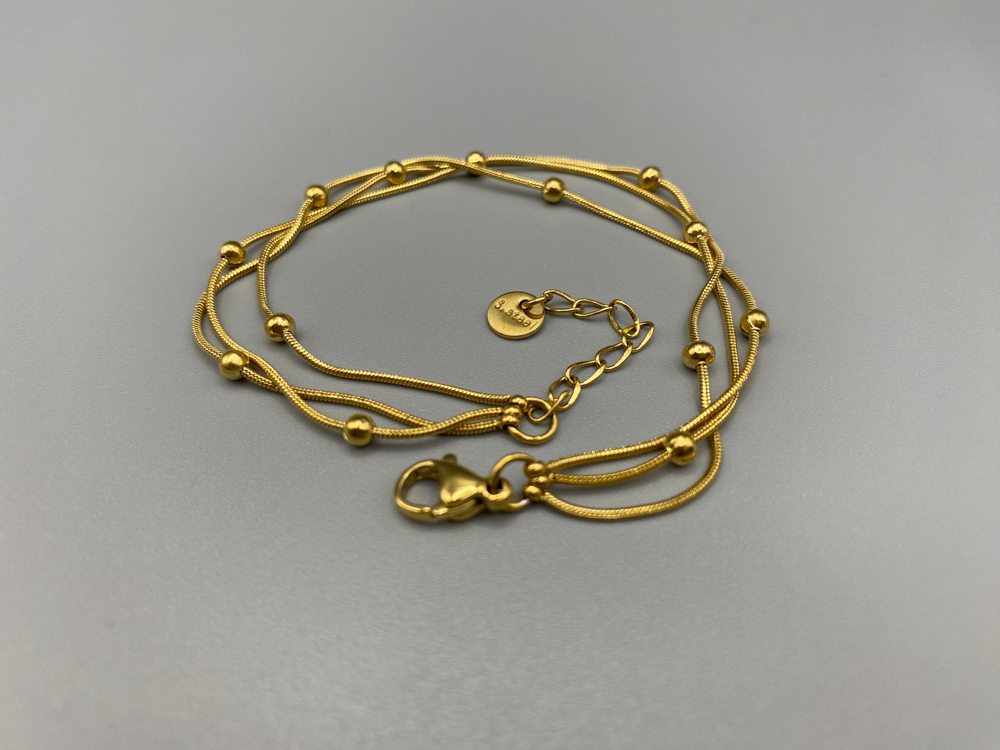 Freya Tri-Chained Bead Bracelet in gold with three delicate chains and evenly spaced small beads. 18K gold plated, made from durable stainless steel with PVD plating. Measures 18 cm with a 3 cm extender for adjustable fit.”