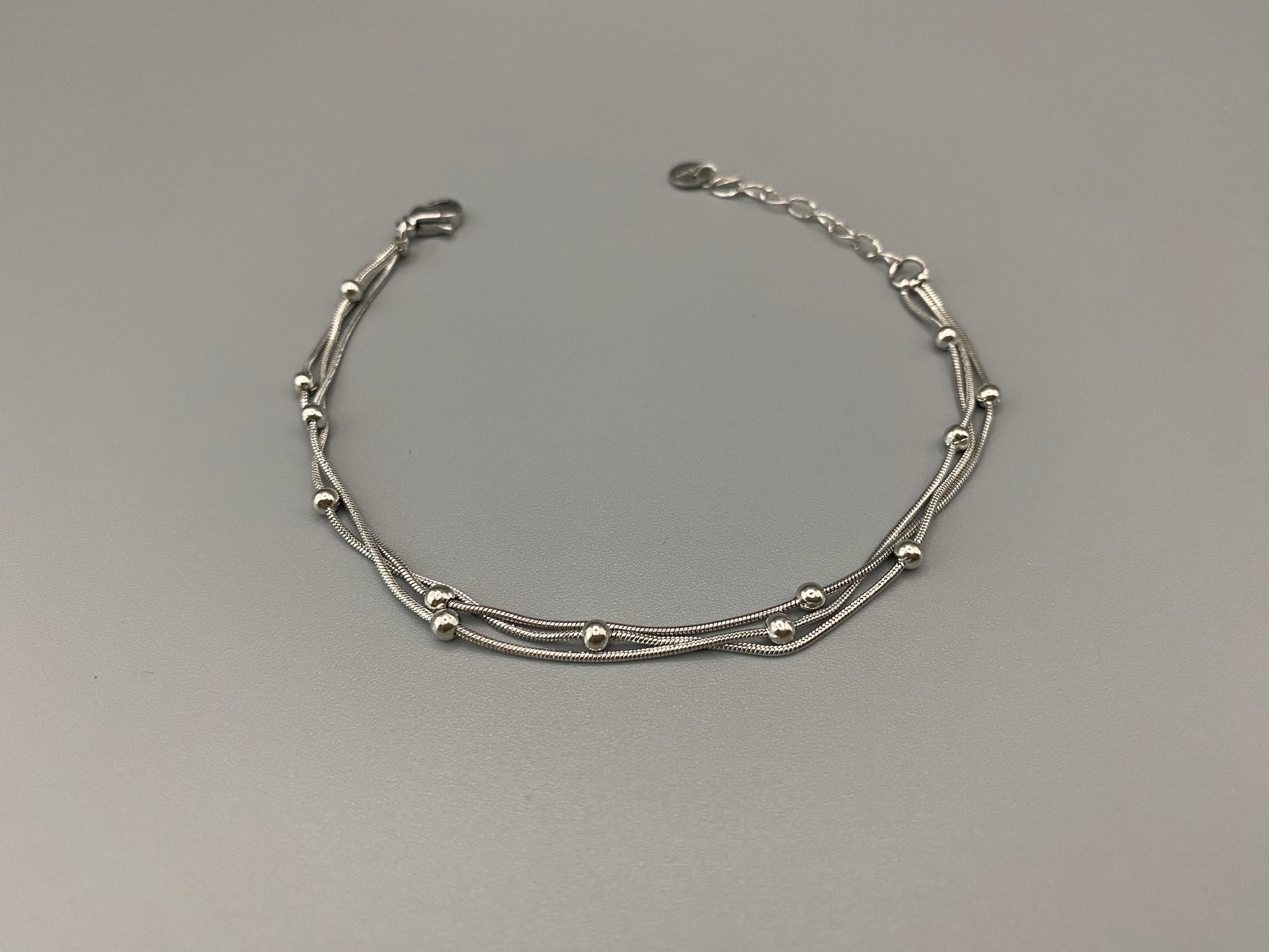 “Freya Tri-Chained Bead Bracelet in silver with three delicate chains and evenly spaced small beads. Silver plated, made from durable stainless steel with PVD plating. Measures 18 cm with a 3 cm extender for adjustable fit.”