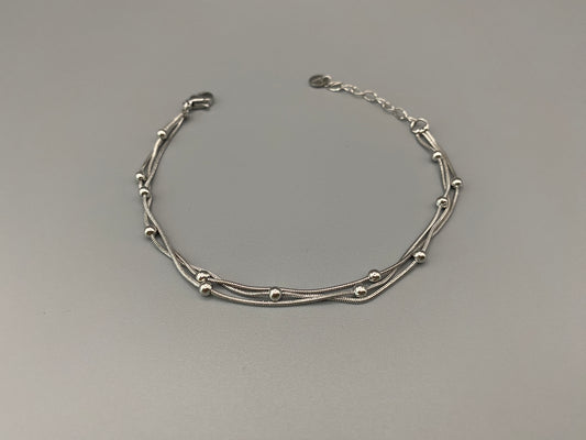 “Freya Tri-Chained Bead Bracelet in silver with three delicate chains and evenly spaced small beads. Silver plated, made from durable stainless steel with PVD plating. Measures 18 cm with a 3 cm extender for adjustable fit.”