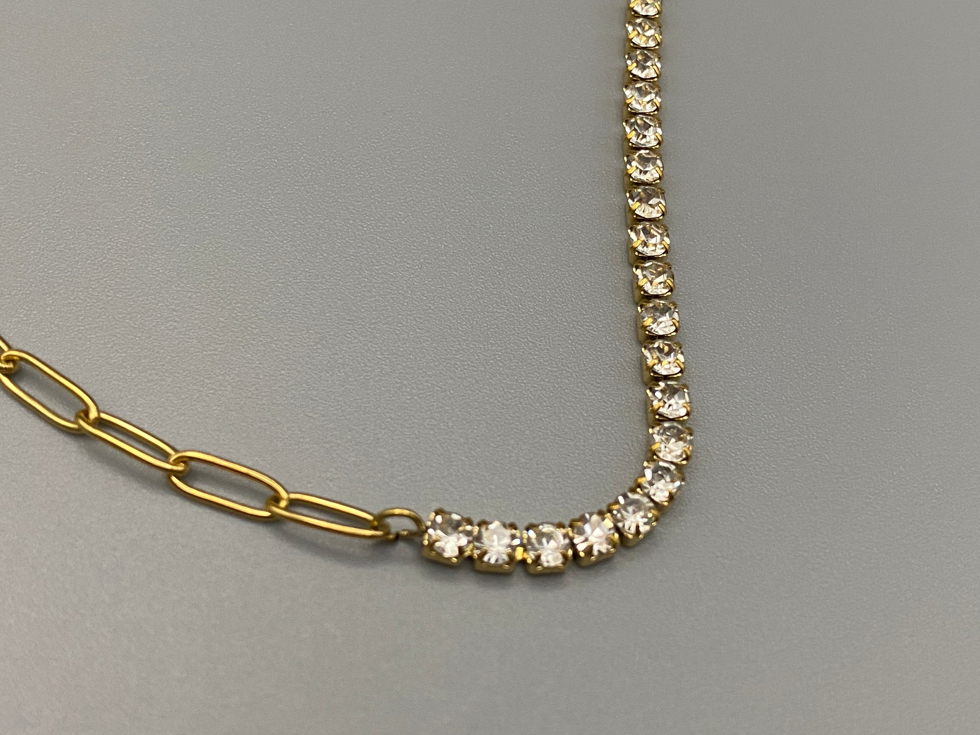 “Gemma Necklace in gold with iced-out zircon paperclip chain, crafted from tarnish-free stainless steel and plated with 18K gold. Measures 45 cm in length with a 5 cm adjustment. Waterproof and perfect for daily wear or special occasions.”