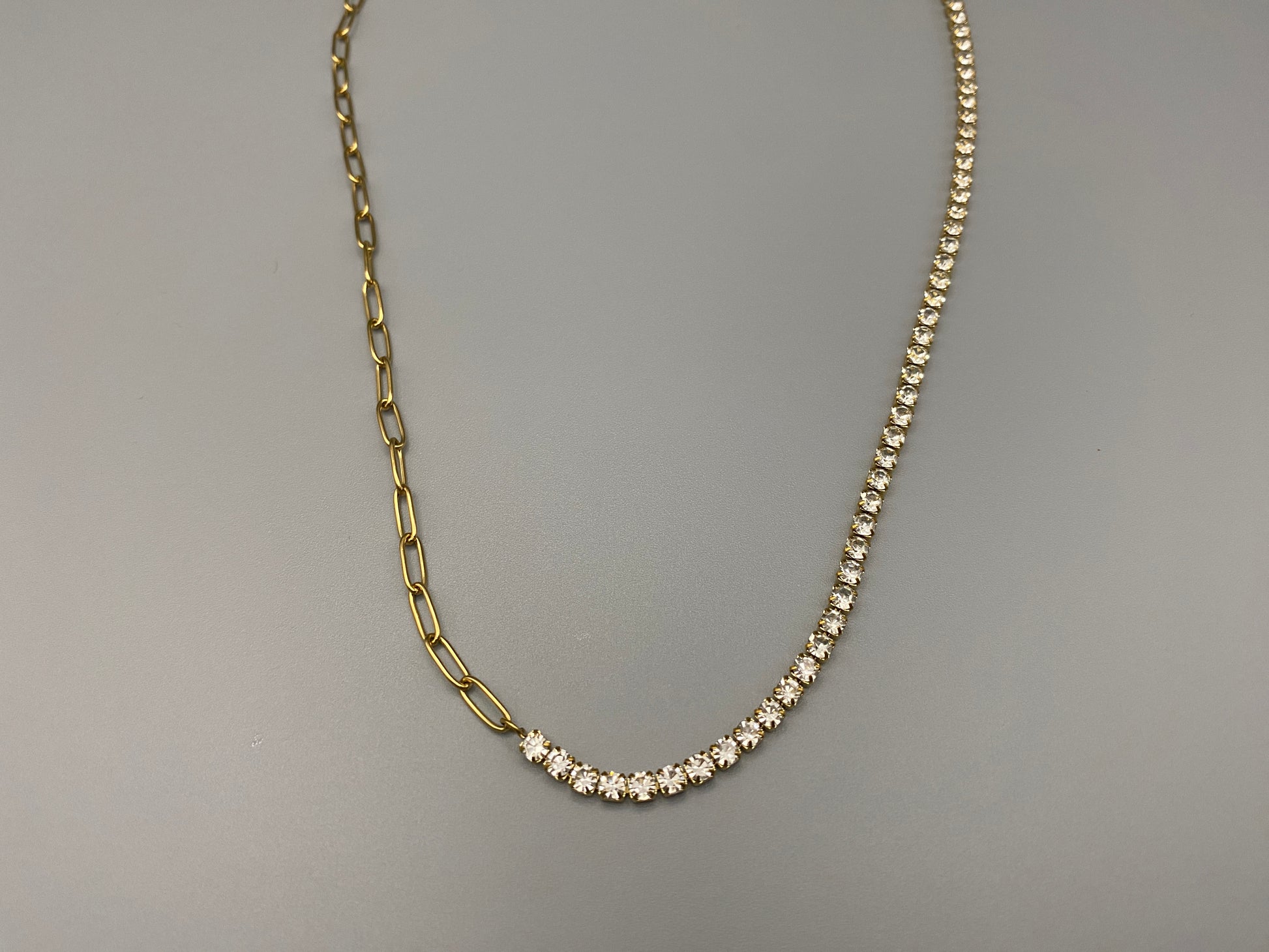 “Gemma Necklace in gold with iced-out zircon paperclip chain, crafted from tarnish-free stainless steel and plated with 18K gold. Measures 45 cm in length with a 5 cm adjustment. Waterproof and perfect for daily wear or special occasions.”