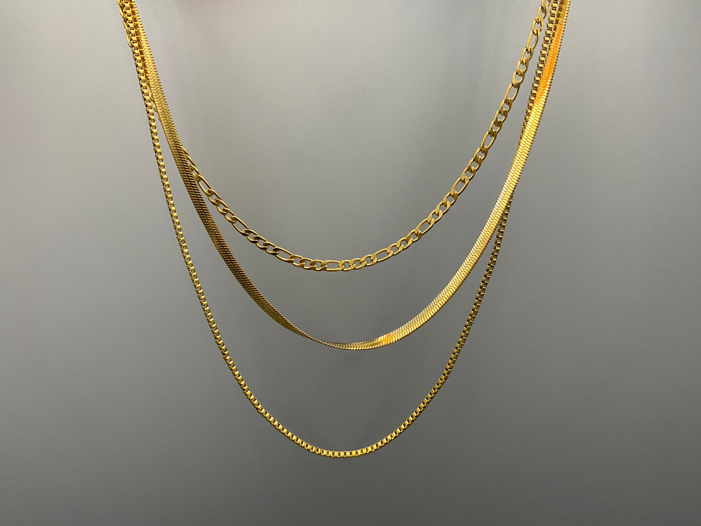 Gina Three Layered Gold Chain Necklace. Three delicate chains layered for a sophisticated look. 18k gold plated, PVD plated for durability. Stainless steel, corrosion-resistant. Adjustable length: 40 cm + 5 cm extender. Versatile for casual and formal wear.
