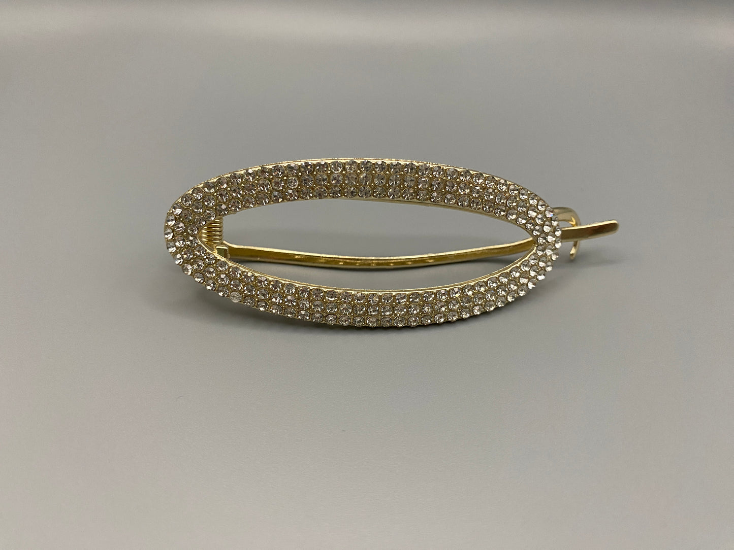 GlitzGrip Hollow Gold Hair Clip featuring a hollow oval design with “sparkling zircon gems, measuring 9.5 cm in length. Elegant and durable, perfect for various hairstyles.”