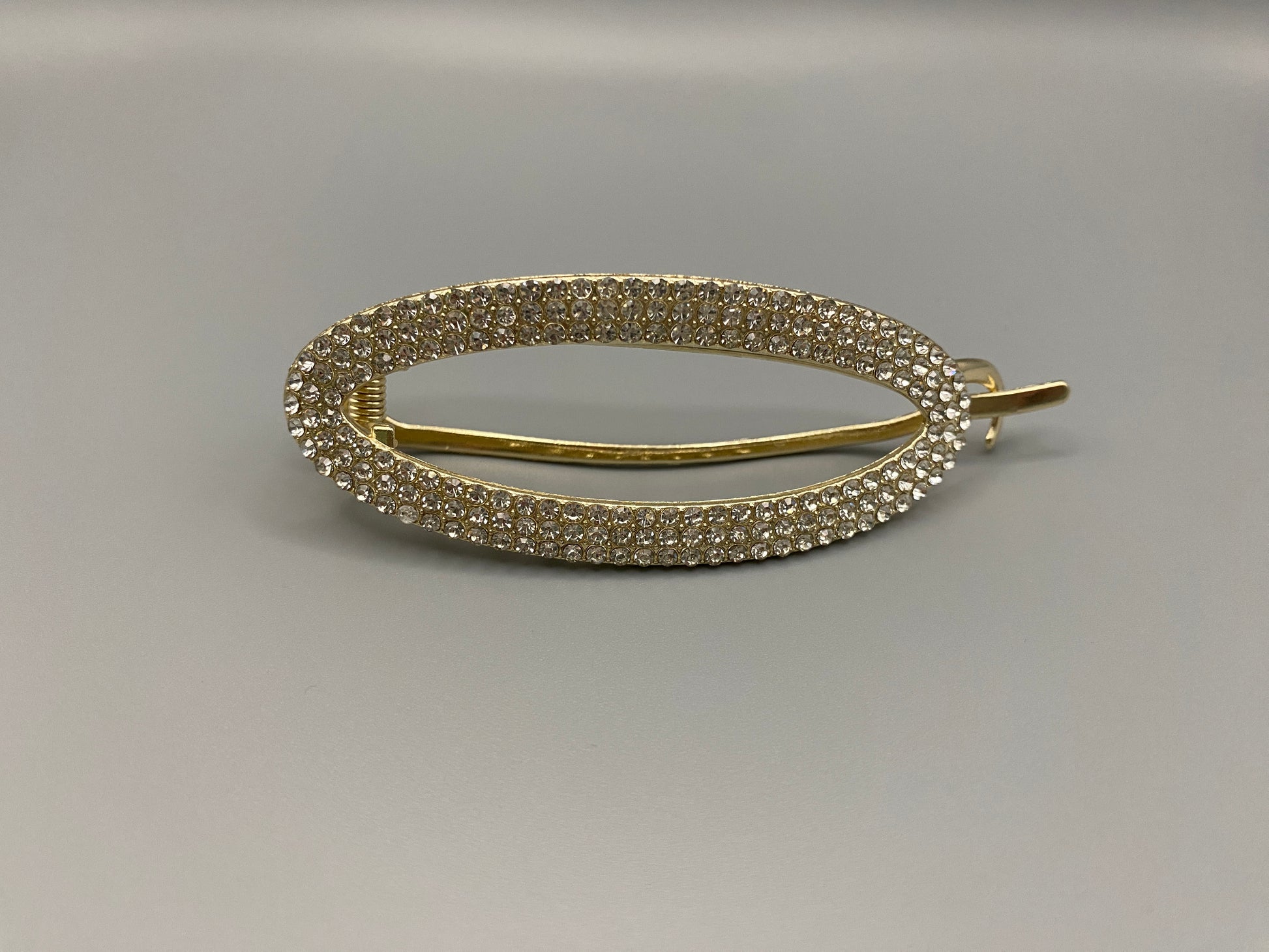 GlitzGrip Hollow Gold Hair Clip featuring a hollow oval design with “sparkling zircon gems, measuring 9.5 cm in length. Elegant and durable, perfect for various hairstyles.”