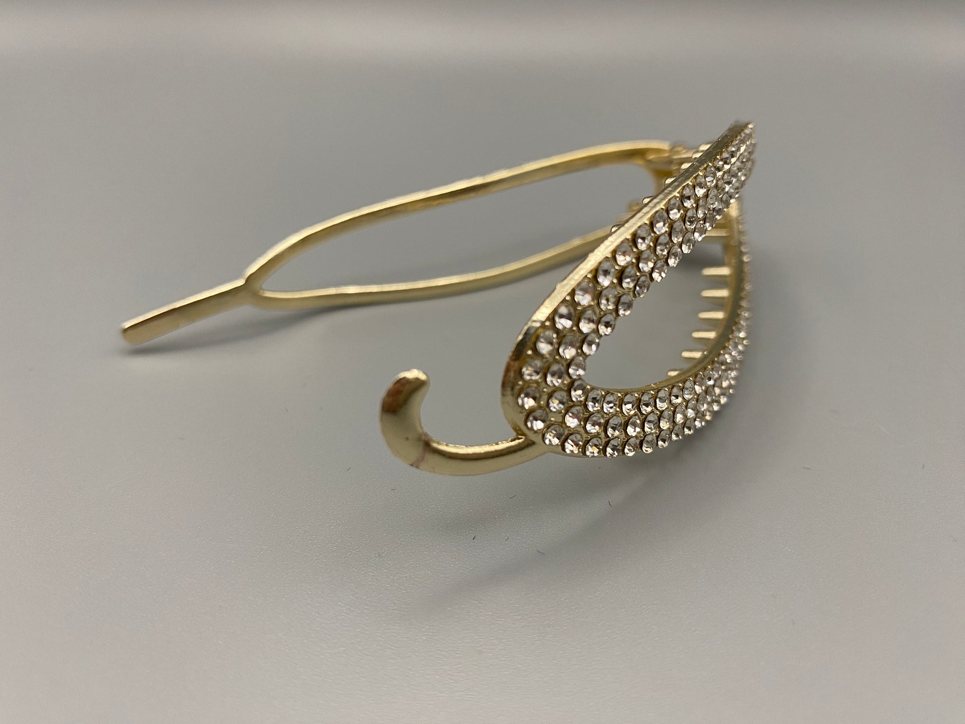 GlitzGrip Hollow Gold Hair Clip featuring a hollow oval design with “sparkling zircon gems, measuring 9.5 cm in length. Elegant and durable, perfect for various hairstyles.”