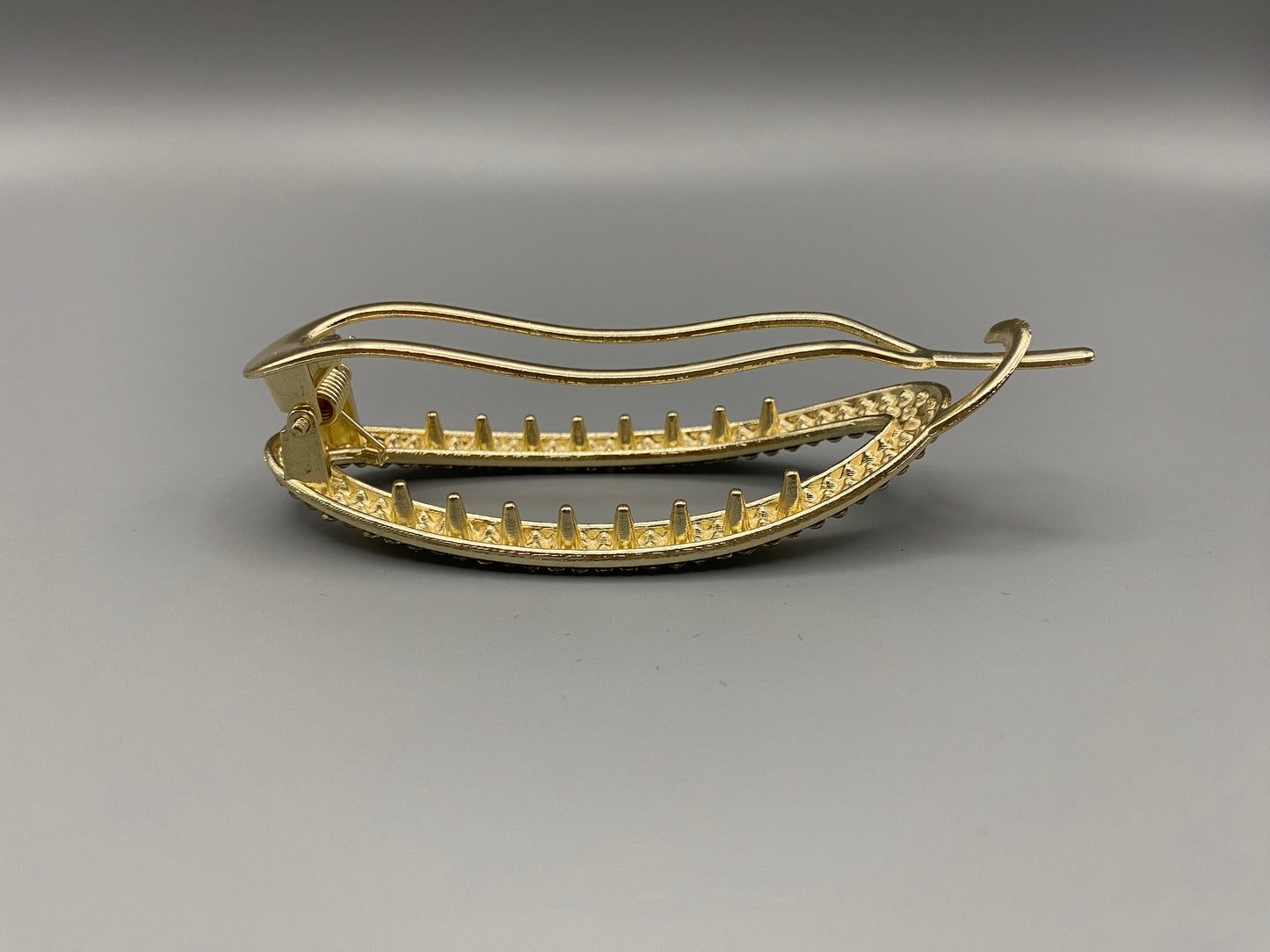 GlitzGrip Hollow Gold Hair Clip featuring a hollow oval design with “sparkling zircon gems, measuring 9.5 cm in length. Elegant and durable, perfect for various hairstyles.”
