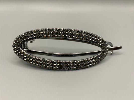 “GlitzGrip Oval Hollow Silver Hair Clip with a hollow oval design, encrusted with sparkling zircon gems. Measures 9.5 cm in length, offering a secure hold for various hair types and styles. Elegant and durable, perfect for both casual and formal hairstyles.”
