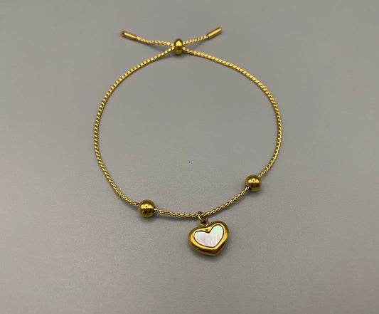 “Helena Heart Bracelet in gold with a white shell heart pendant, crafted from high-quality stainless steel and plated with 18K gold. Adjustable, waterproof, tarnish-free, and environmentally friendly.”