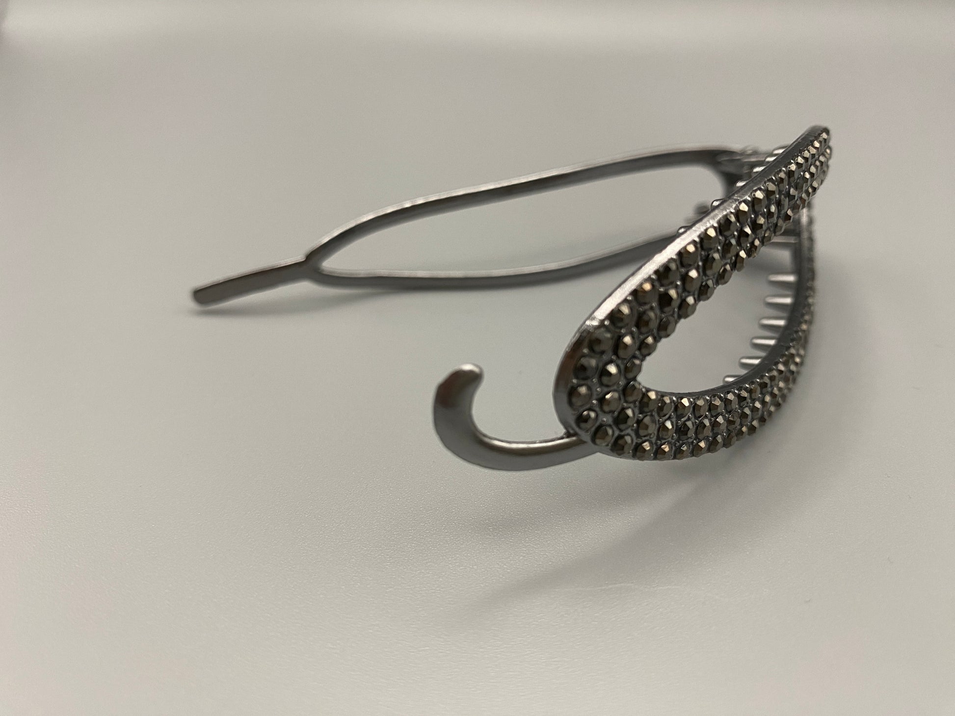 “GlitzGrip Oval Hollow Silver Hair Clip with a hollow oval design, encrusted with sparkling zircon gems. Measures 9.5 cm in length, offering a secure hold for various hair types and styles. Elegant and durable, perfect for both casual and formal hairstyles.”