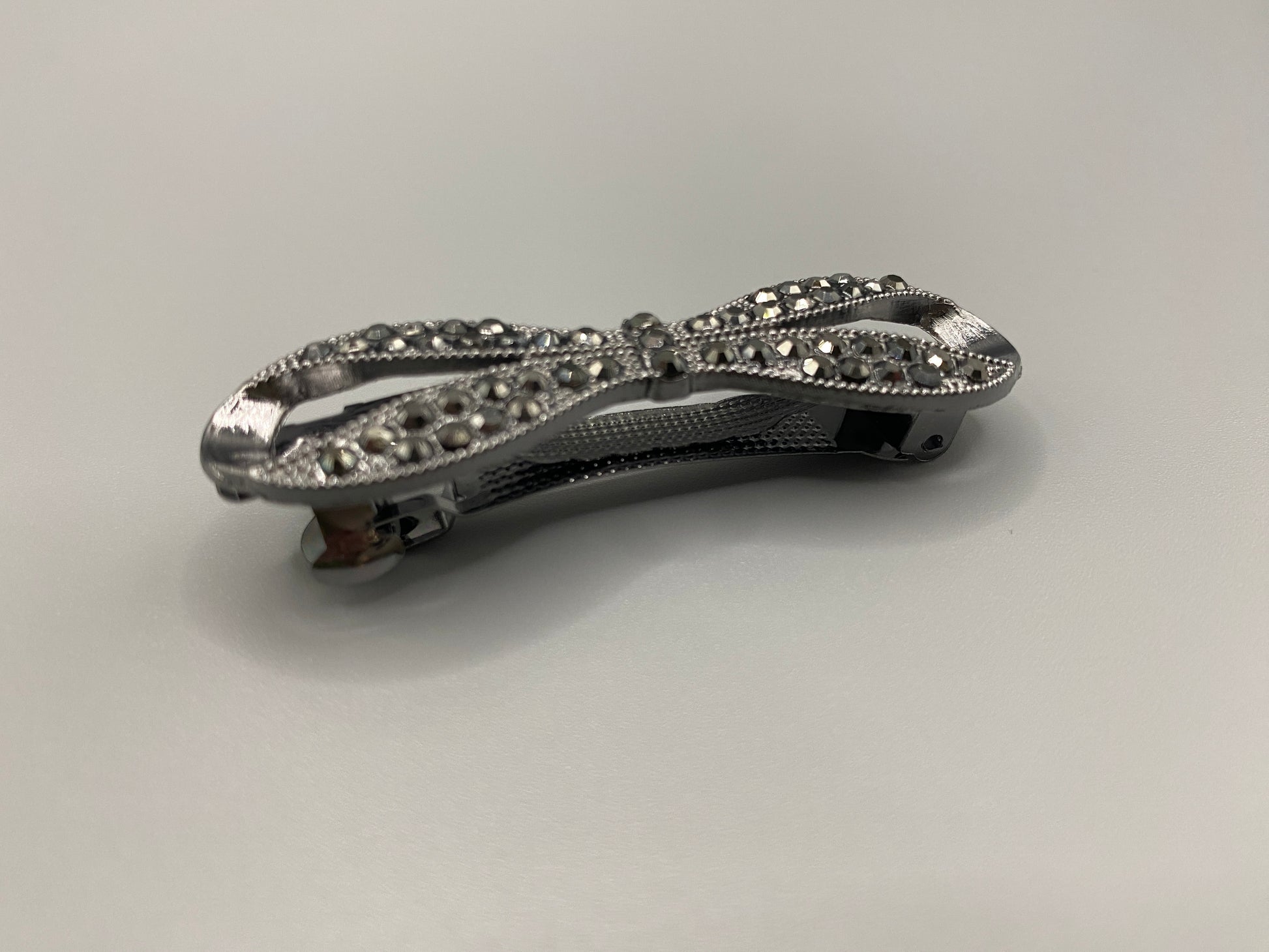 Jasmine Dazzling Hair Clip in Black with a rhinestone bow design featuring sparkling black zirconia inset stones. Measure 6 cm, crafted from high-quality metal for durability. Elegant and versatile, perfect for both special occasions and everyday wear.”