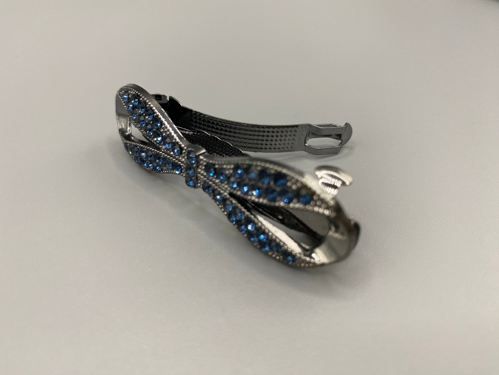 “Jasmine Dazzling Hair Clip in Blue with a rhinestone bow design featuring sparkling blue zirconia inset stones. Measures 6cm, crafted from high-quality metal for durability. Elegant and versatile, perfect for both special occasions and everyday wear.”