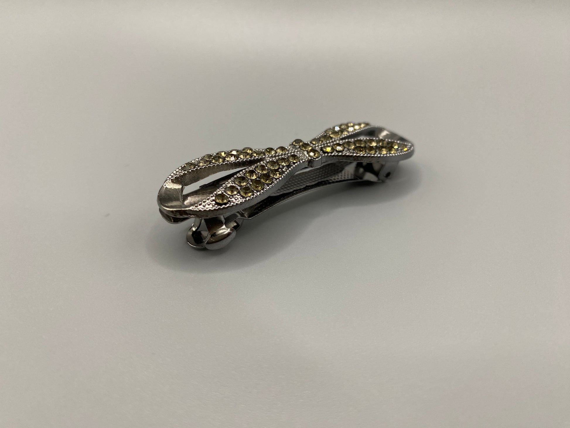 “Jasmine Dazzling Hair Pin in Silver Yellow with a rhinestone bow design featuring sparkling yellow zirconia inset stones. Measures 8x3x3 cm, crafted from high-quality metal for durability. Elegant and versatile, perfect for both special occasions and everyday wear.”