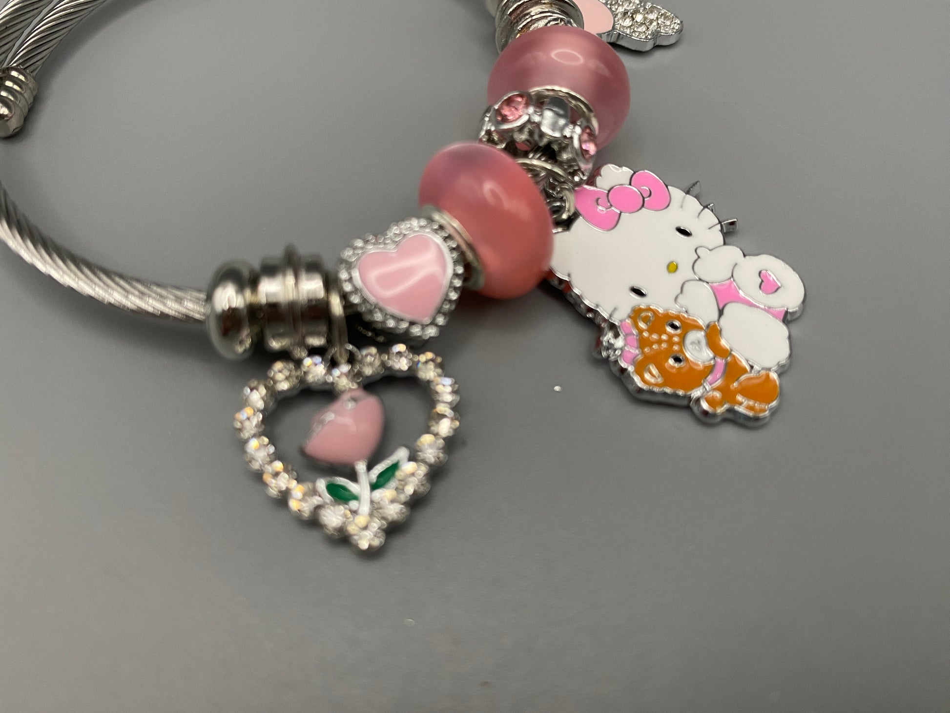 Kitty Cartoon Character Bracelet in pink with stainless steel bangles, adorned with alloy charms, crystals, and glass beads. Features a charm with pink accents, combining playful elegance and sophistication.”