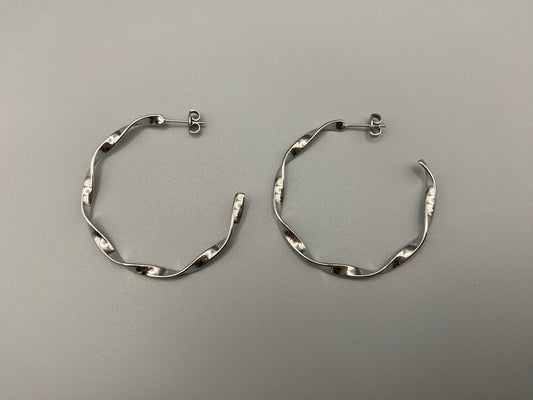 “Leanne C Shape Earrings Silver: Fashion-forward twisted wire earrings with an irregular C-shaped design, crafted from high-quality stainless steel and plated with luxurious silver. Perfect for any occasion.”