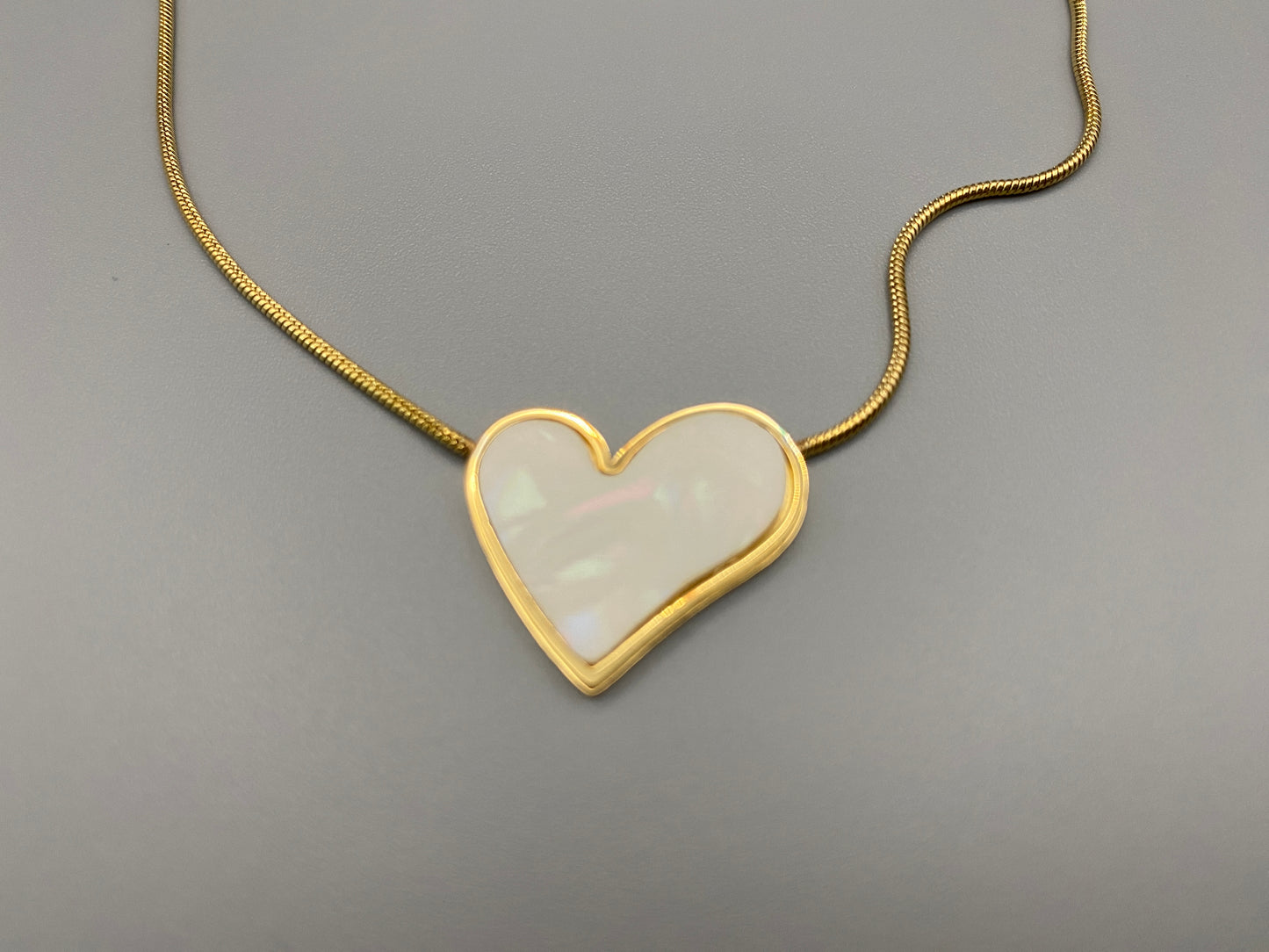 Paris Beige Heart Necklace. Big love heart pendant on a sleek snake chain. High-quality stainless steel, gold-plated. Measures 46 cm + 5 cm adjustment. Elegant princess cut heart pendant. Versatile for daily wear or special occasions.