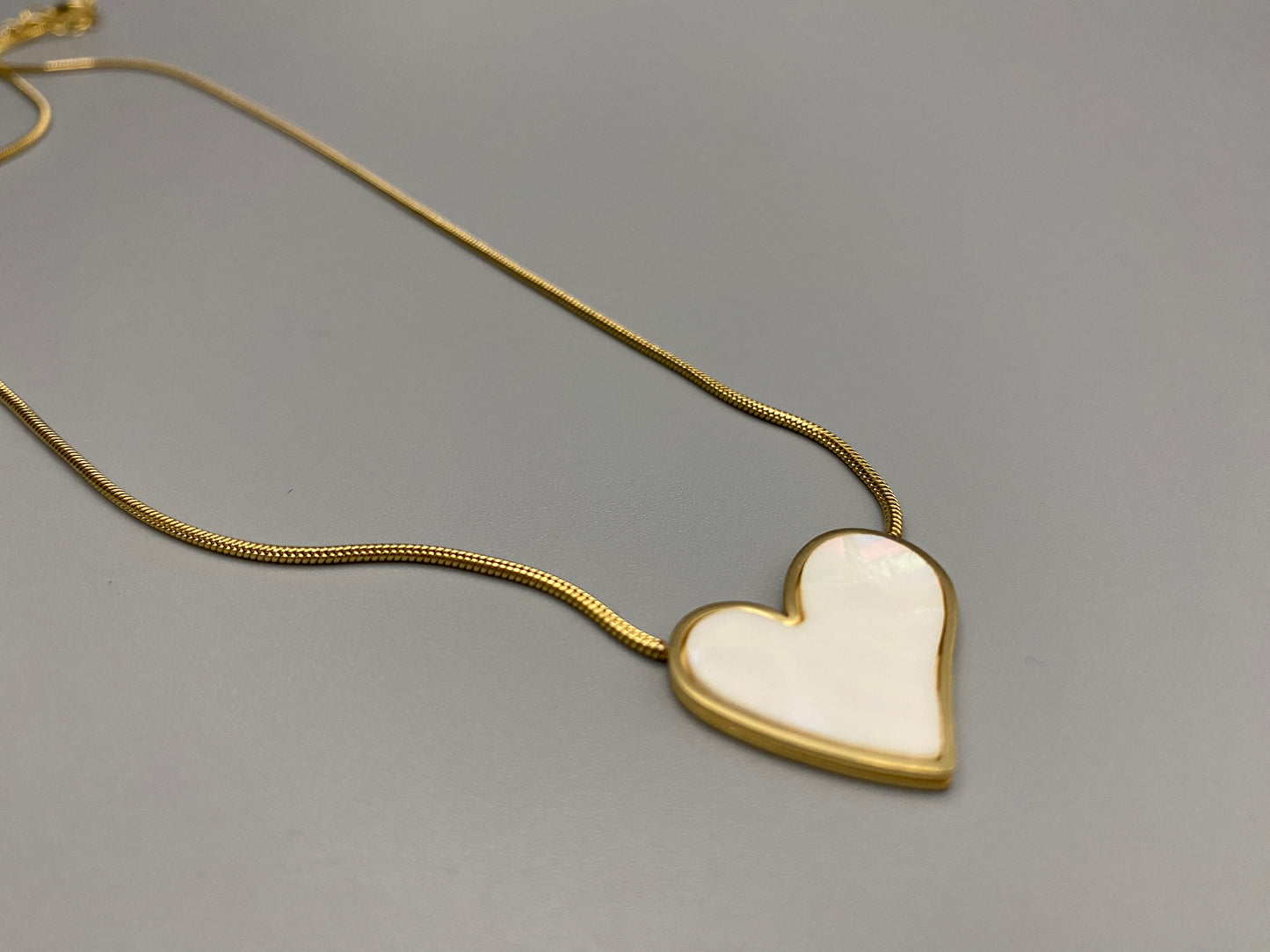 Paris Beige Heart Necklace. Big love heart pendant on a sleek snake chain. High-quality stainless steel, gold-plated. Measures 46 cm + 5 cm adjustment. Elegant princess cut heart pendant. Versatile for daily wear or special occasions.