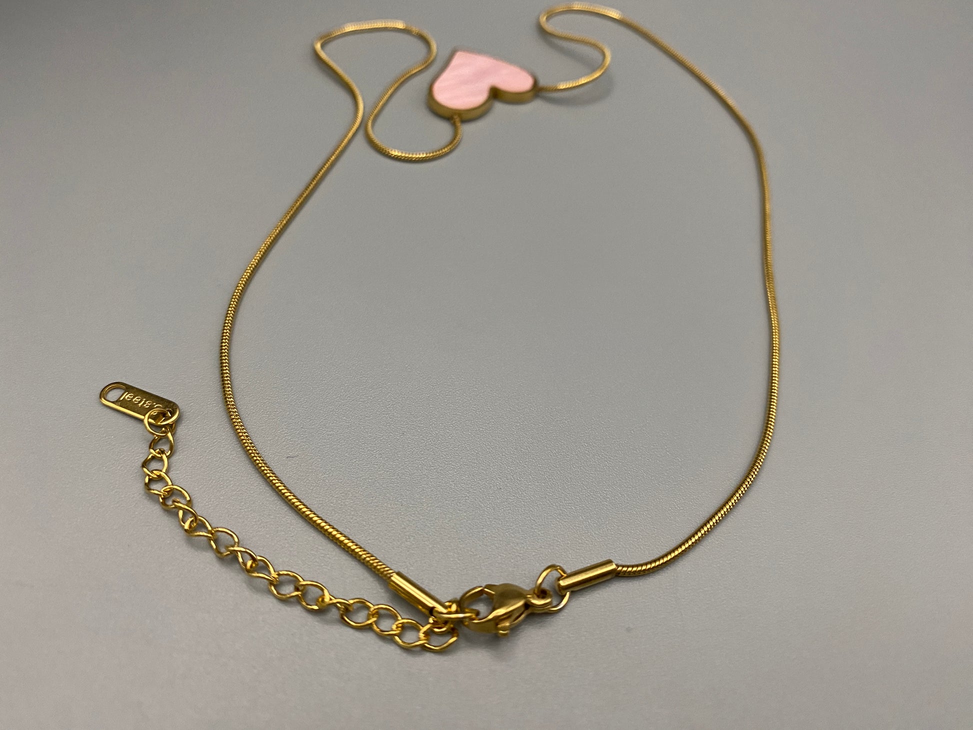 Paris Pink Heart Necklace. Big love heart pendant on a sleek snake chain. High-quality stainless steel, gold-plated. Measures 46 cm + 5 cm adjustment. Elegant princess cut heart pendant. Versatile for daily wear or special occasions.