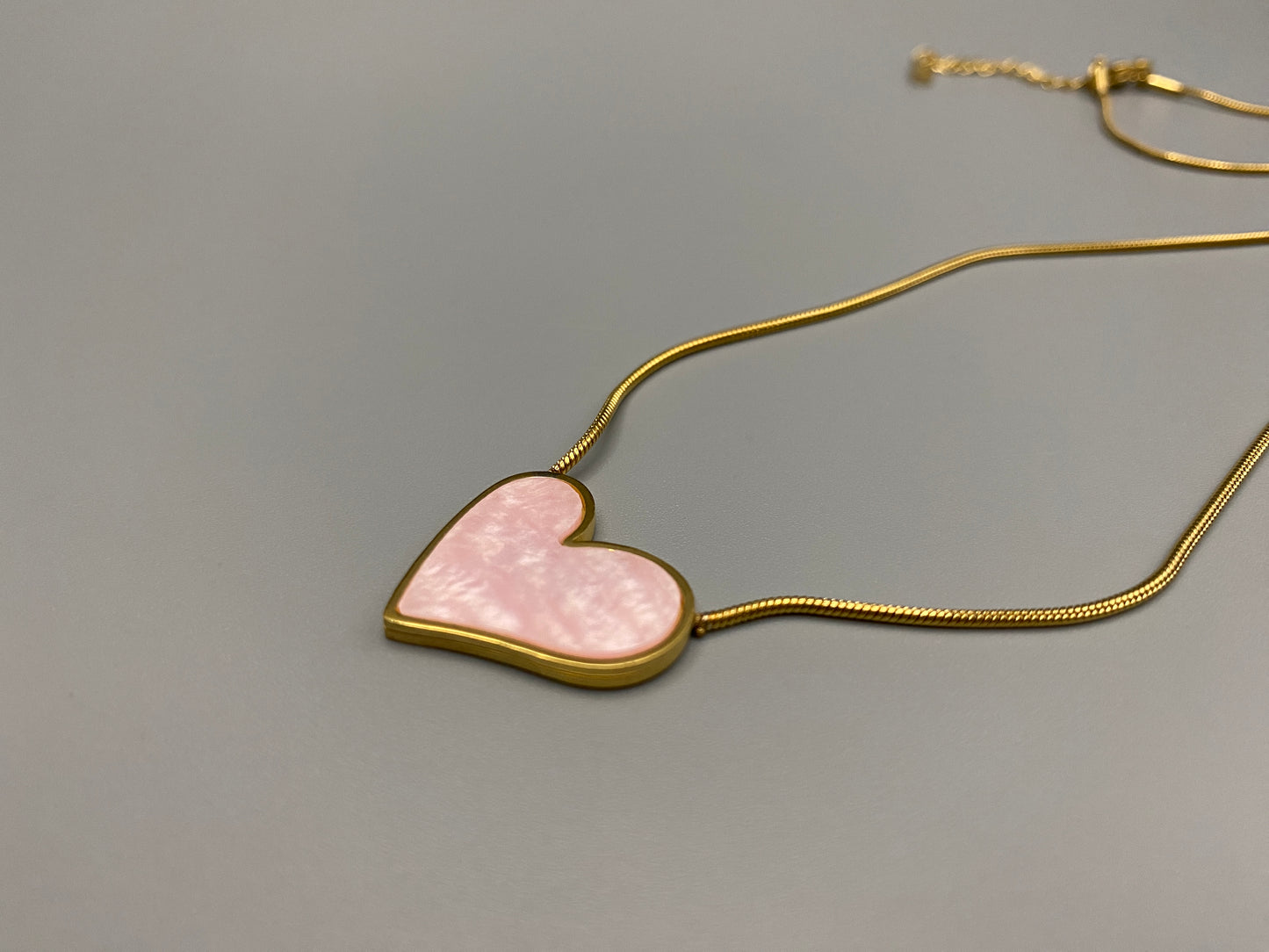 Paris Pink Heart Necklace. Big love heart pendant on a sleek snake chain. High-quality stainless steel, gold-plated. Measures 46 cm + 5 cm adjustment. Elegant princess cut heart pendant. Versatile for daily wear or special occasions.