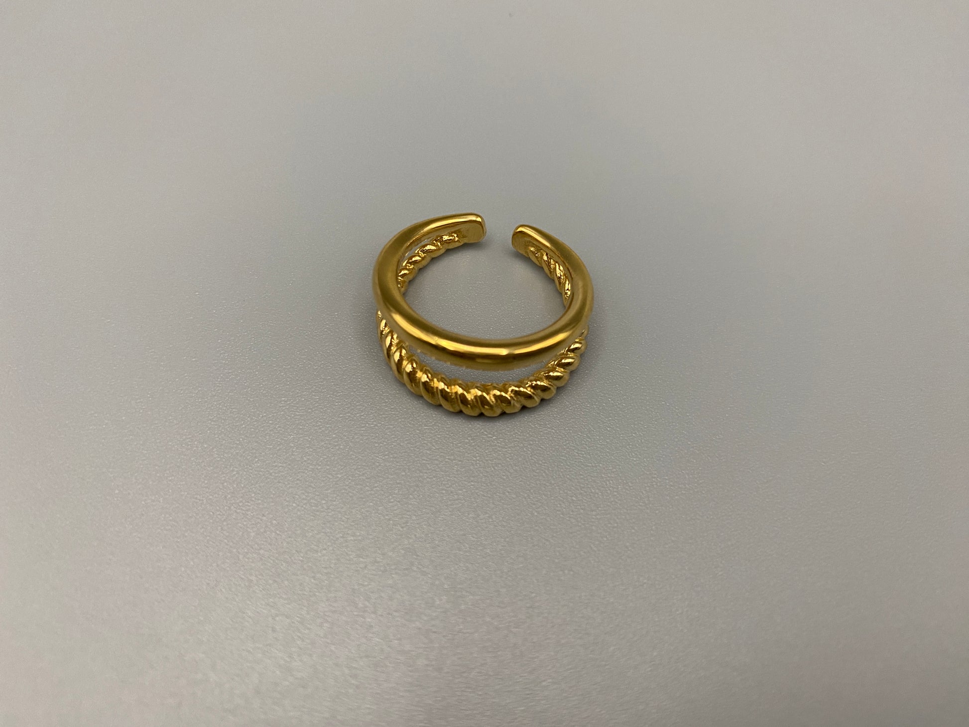 Selene Twin Band Ring Gold: This ring features a unique combination of a textured rope band and a smooth plain band, both gold plated for a luxurious finish. The titanium PVD ensures durability and resistance to wear, while the stainless steel construction adds strength and longevity. The unique twin band design combines elegance and modernity. Available in ring size 7, it is perfect for those who wear this size. Make a statement with this versatile and chic accessory that complements any look.