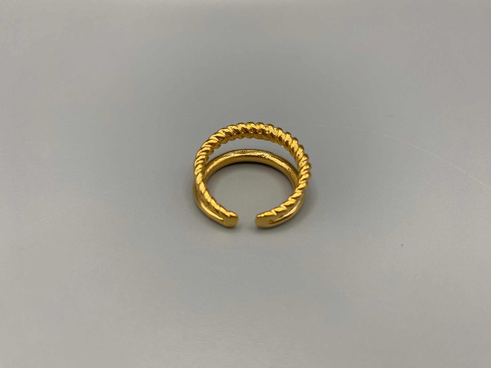 Selene Twin Band Ring Gold: This ring features a unique combination of a textured rope band and a smooth plain band, both gold plated for a luxurious finish. The titanium PVD ensures durability and resistance to wear, while the stainless steel construction adds strength and longevity. The unique twin band design combines elegance and modernity. Available in ring size 7, it is perfect for those who wear this size. Make a statement with this versatile and chic accessory that complements any look.