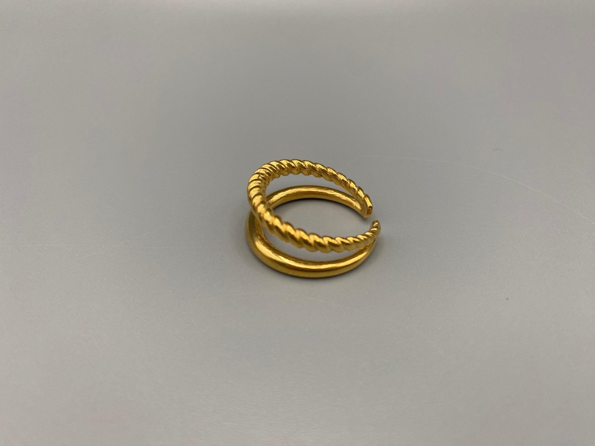 Selene Twin Band Ring Gold: This ring features a unique combination of a textured rope band and a smooth plain band, both gold plated for a luxurious finish. The titanium PVD ensures durability and resistance to wear, while the stainless steel construction adds strength and longevity. The unique twin band design combines elegance and modernity. Available in ring size 7, it is perfect for those who wear this size. Make a statement with this versatile and chic accessory that complements any look.